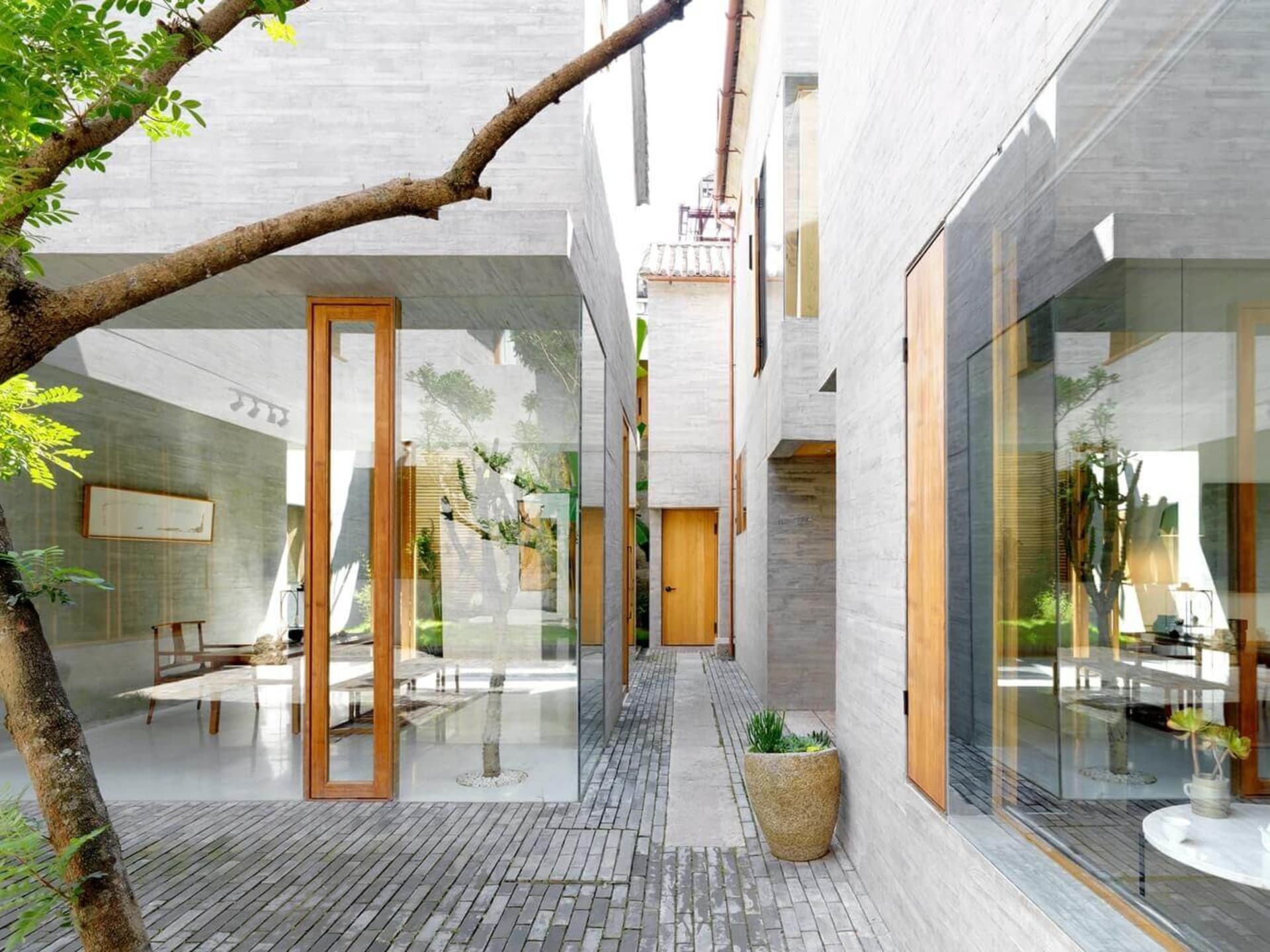Contemporary interior design featuring a minimalist concrete space with large windows and a central courtyard.