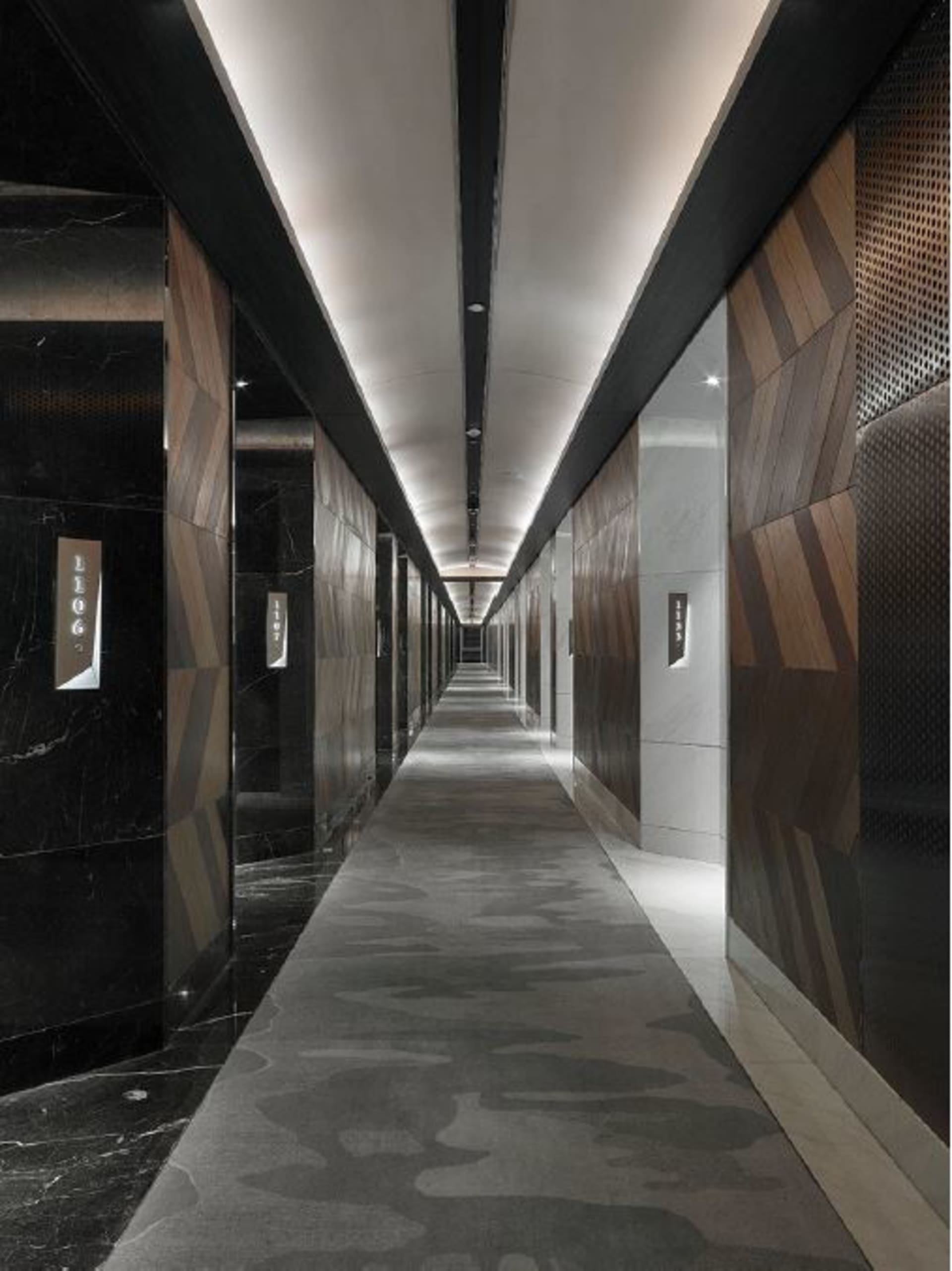 A modern, sleek corridor lined with marble floors, wooden walls, and metallic elements.