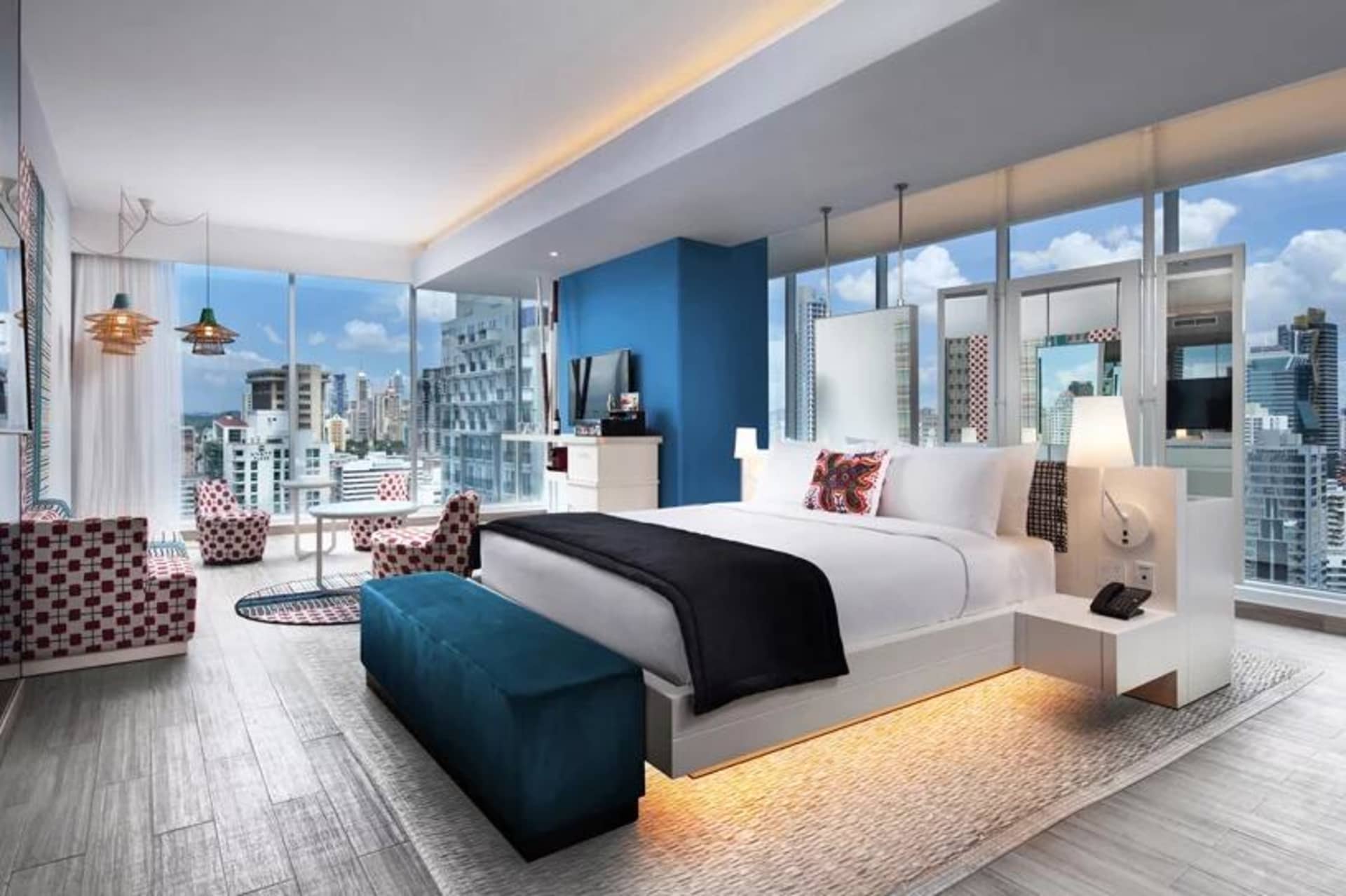 Modern hotel room interior with wooden furniture, fabric accents, glass walls, and metal elements.