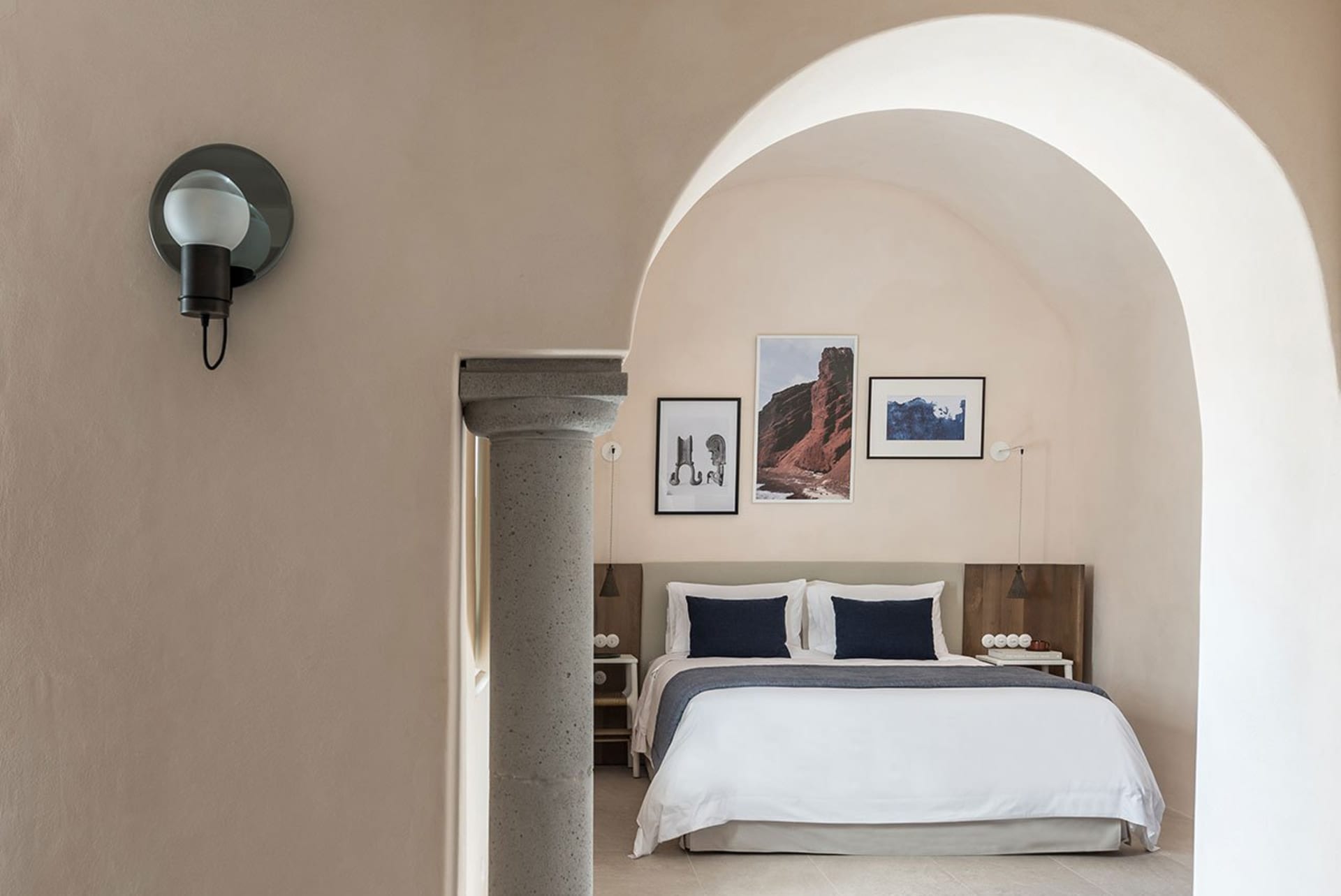A minimalist bedroom with a concrete wall, a wooden bed frame, and fabric bedding.