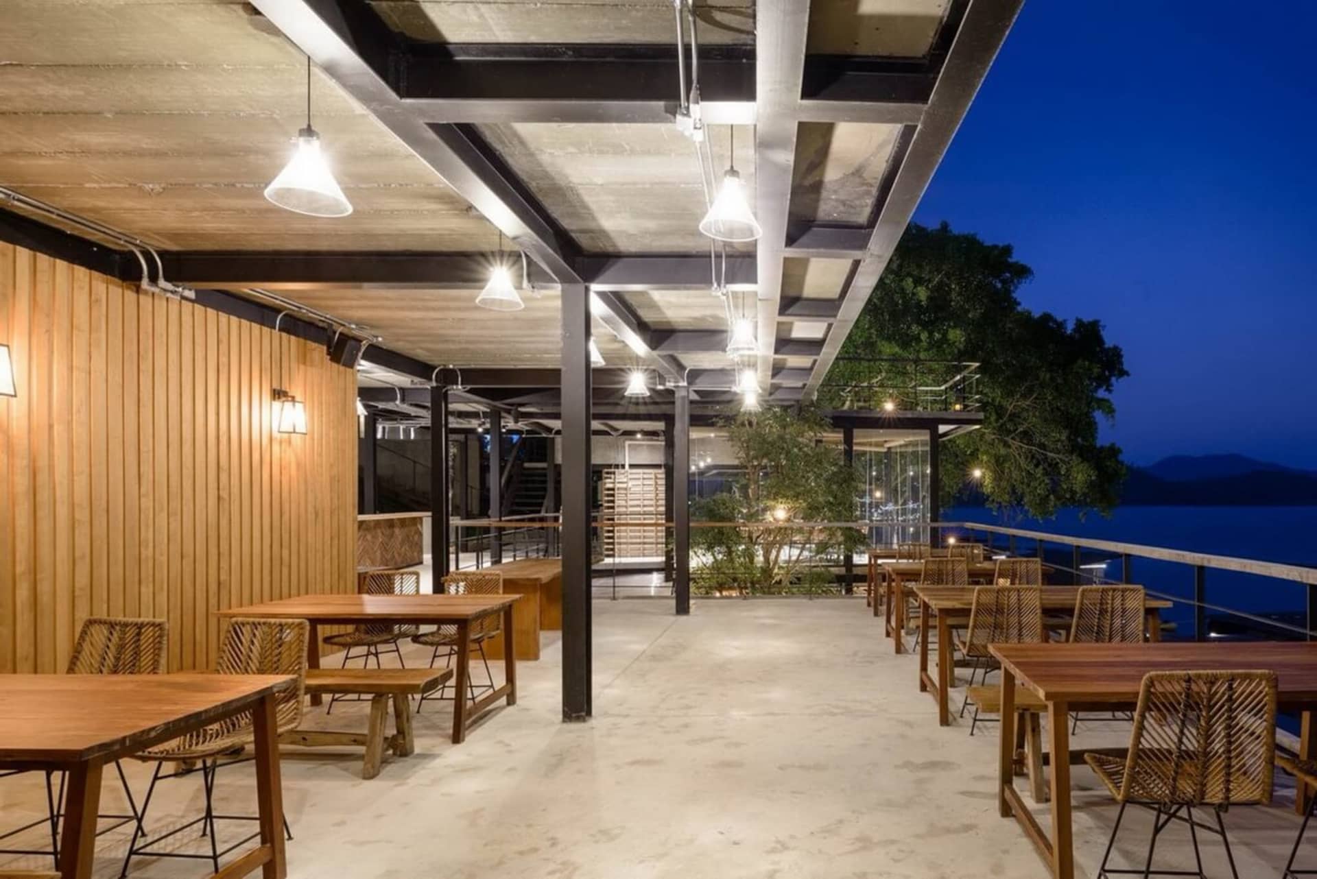 現代工業風餐廳，木製餐桌搭配混凝土地板，鋼樑天花板。