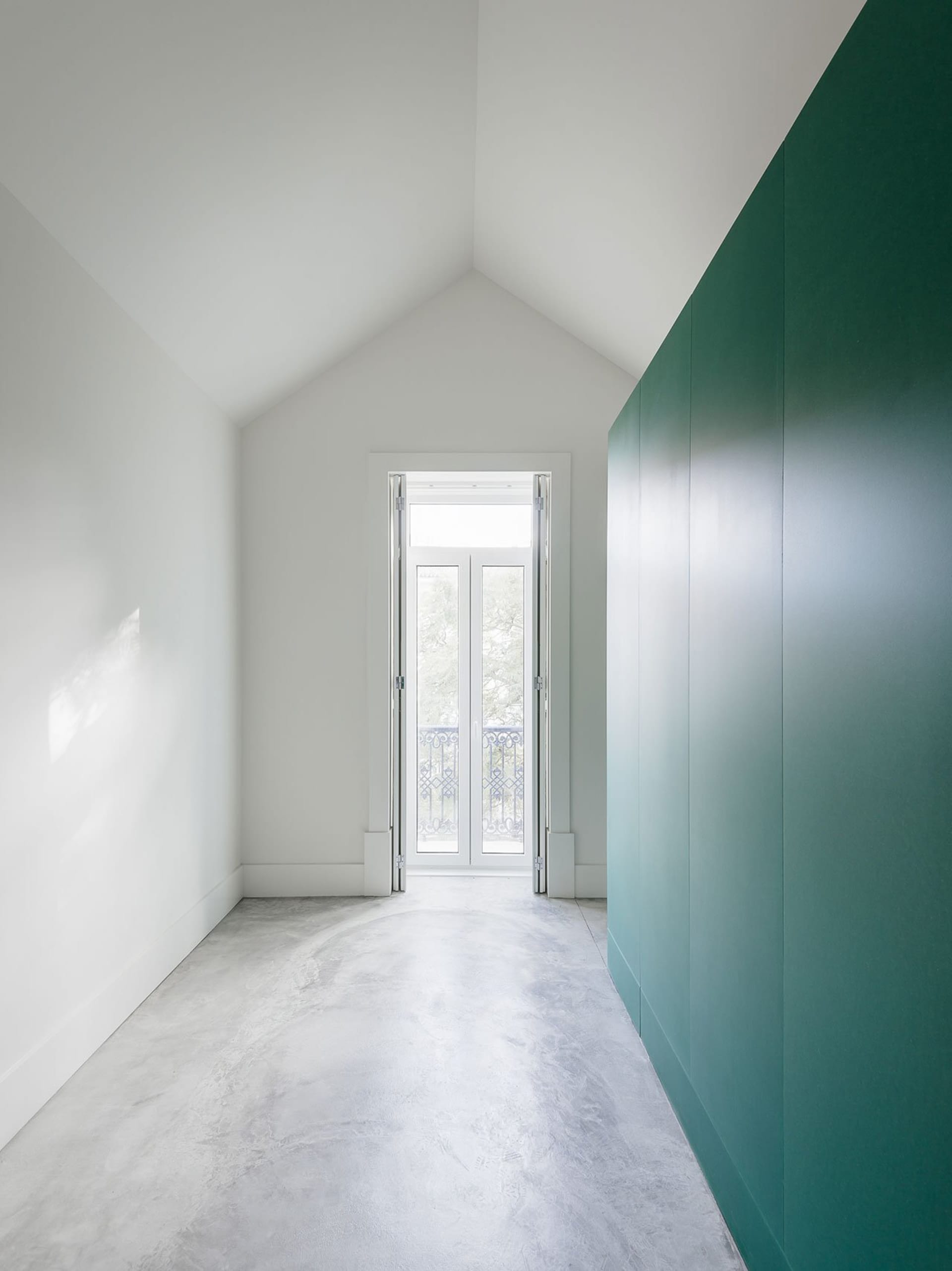A white closet with a green door on a concrete floor.