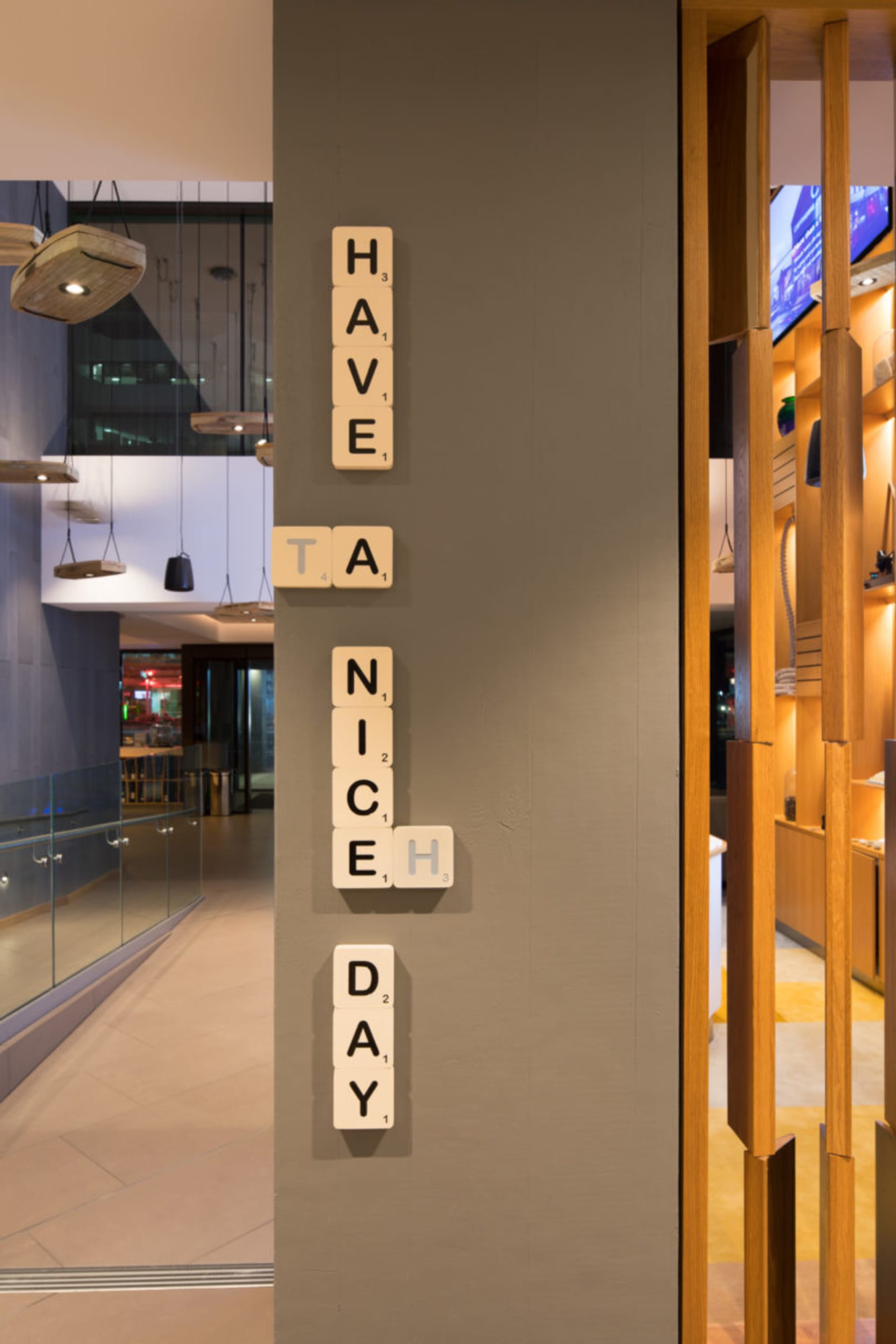 一面牆上掛著工業風木質字母拼板，拼出「HAVE A NICE DAY」。