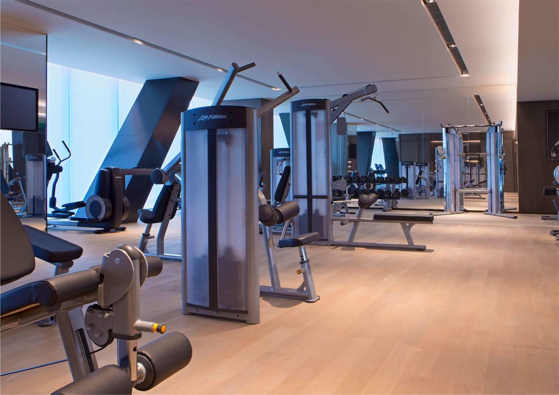 Modern minimalist fitness center with glass walls and metallic equipment.