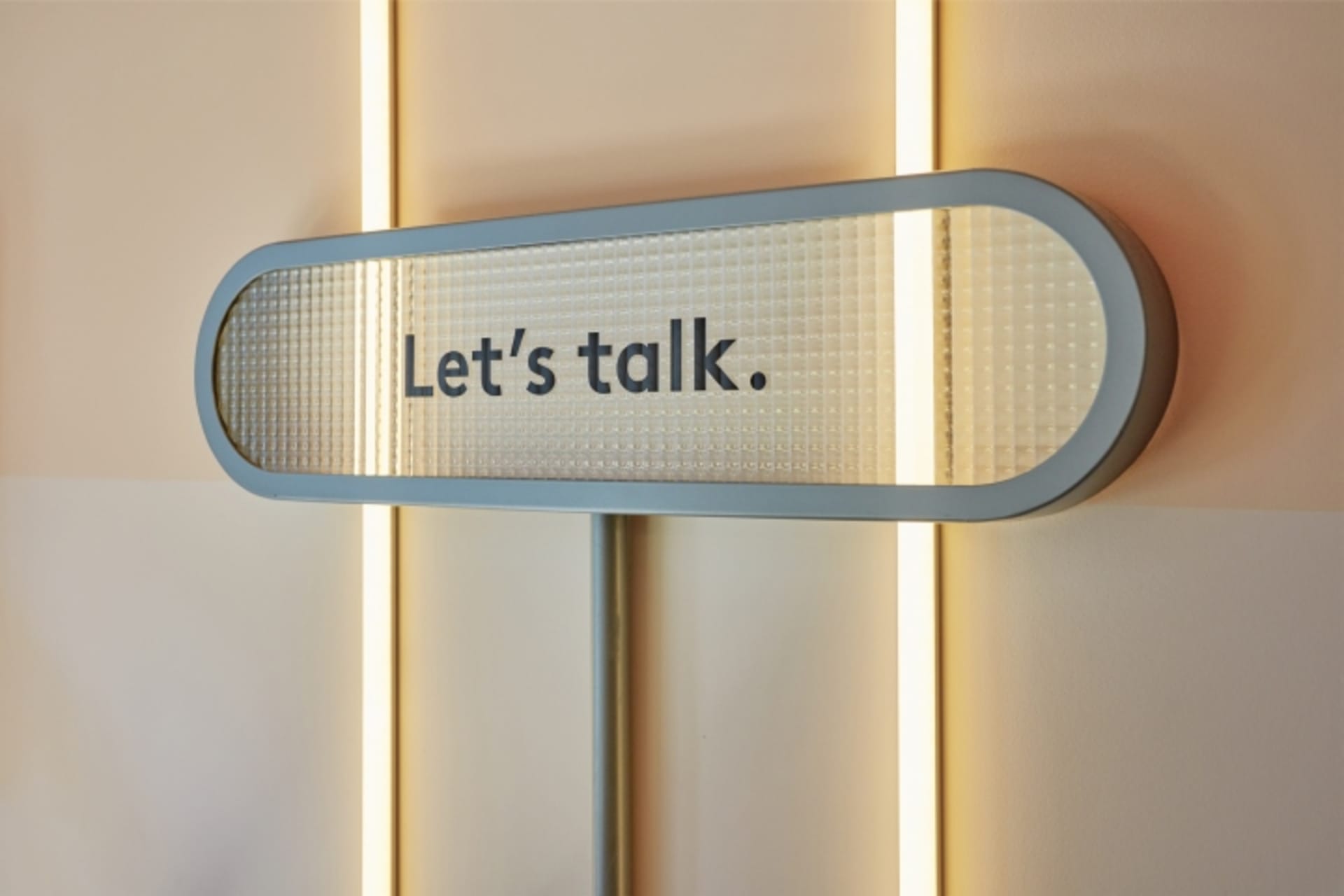 極簡風格的標誌,呈現金屬質感文字,寫著「Let’s talk.」