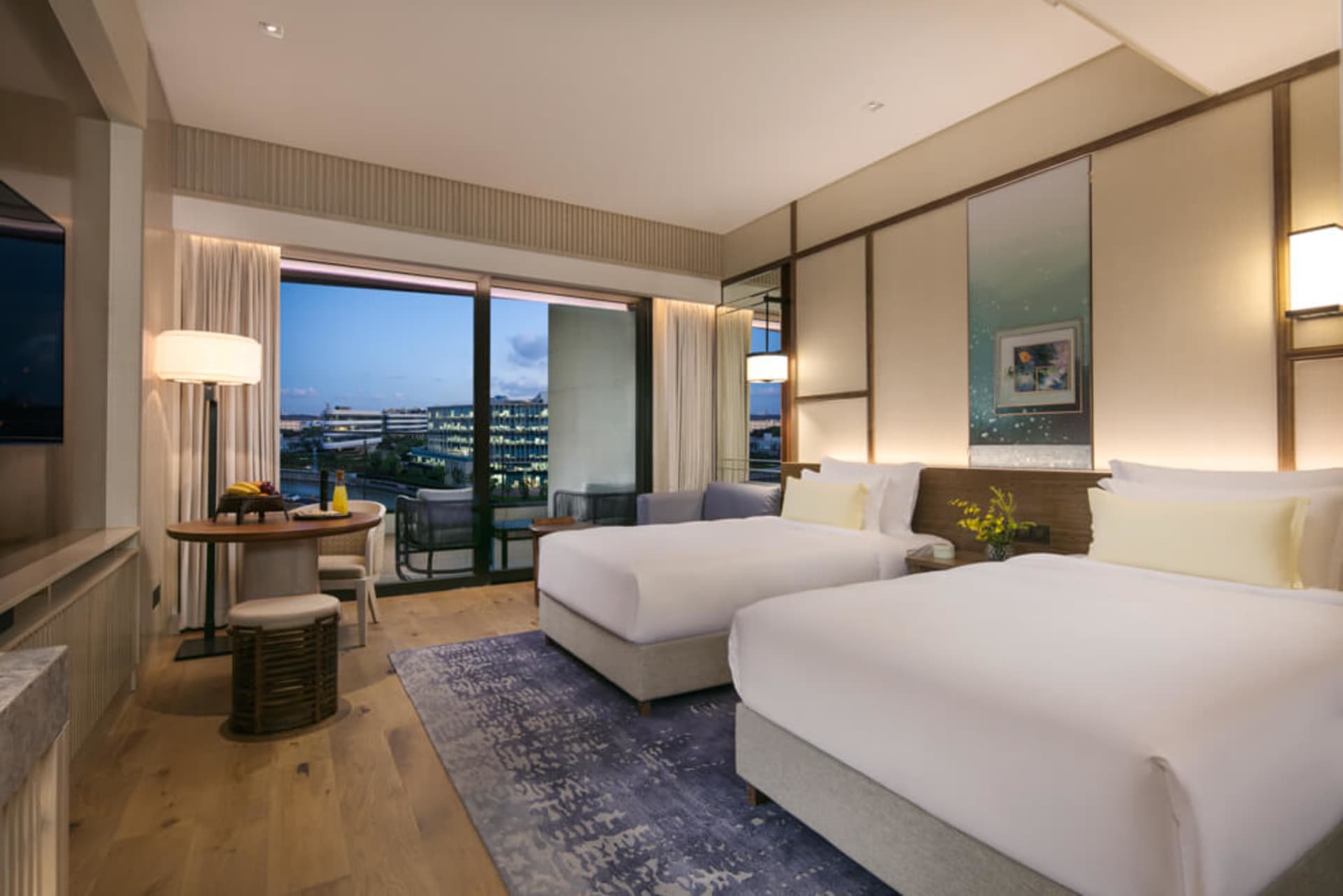 Modern bedroom with white and gray wood flooring, glass window, and two white beds.