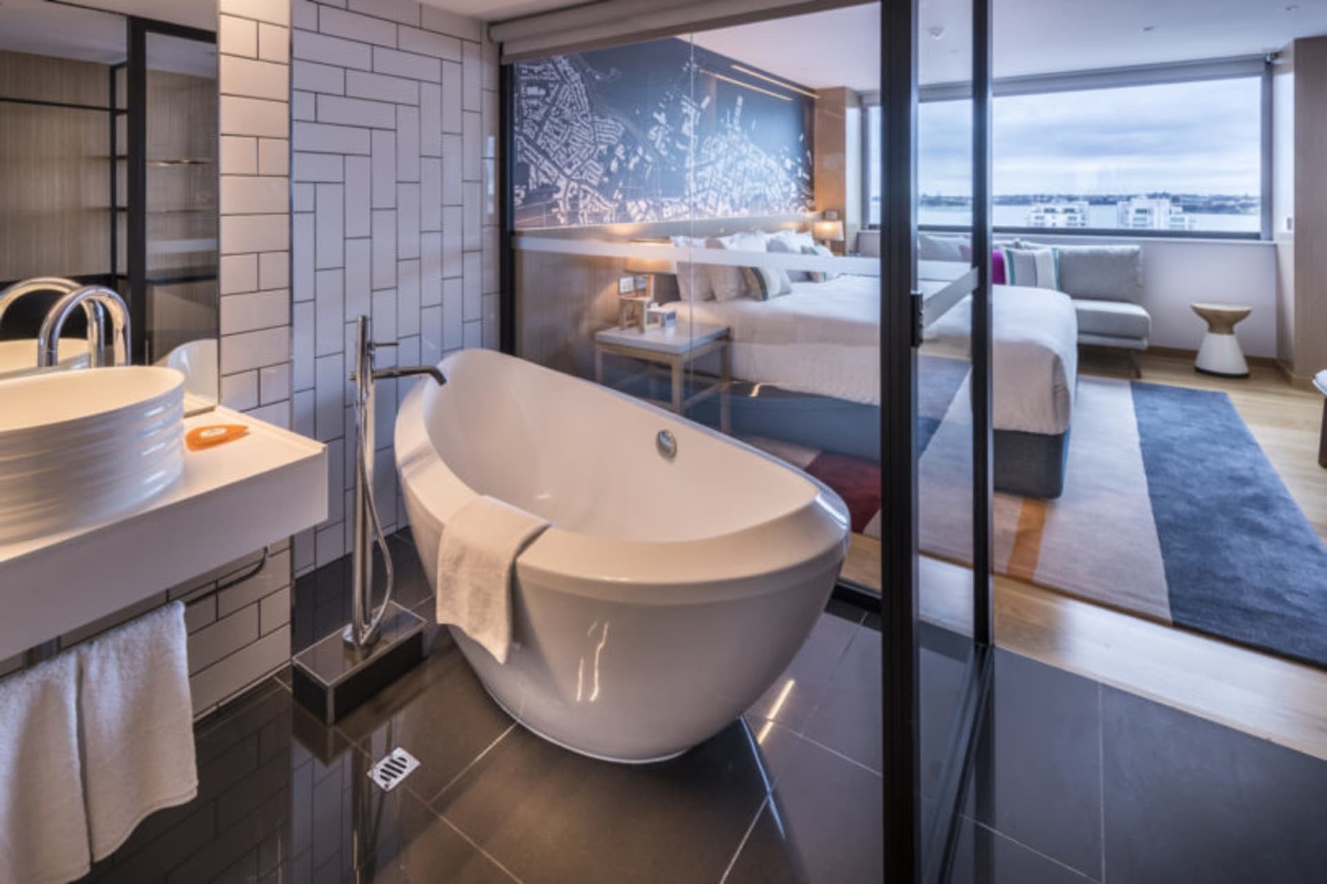 Modern minimalist bathroom with white marble finishes, floor-to-ceiling windows, and a freestanding bathtub.