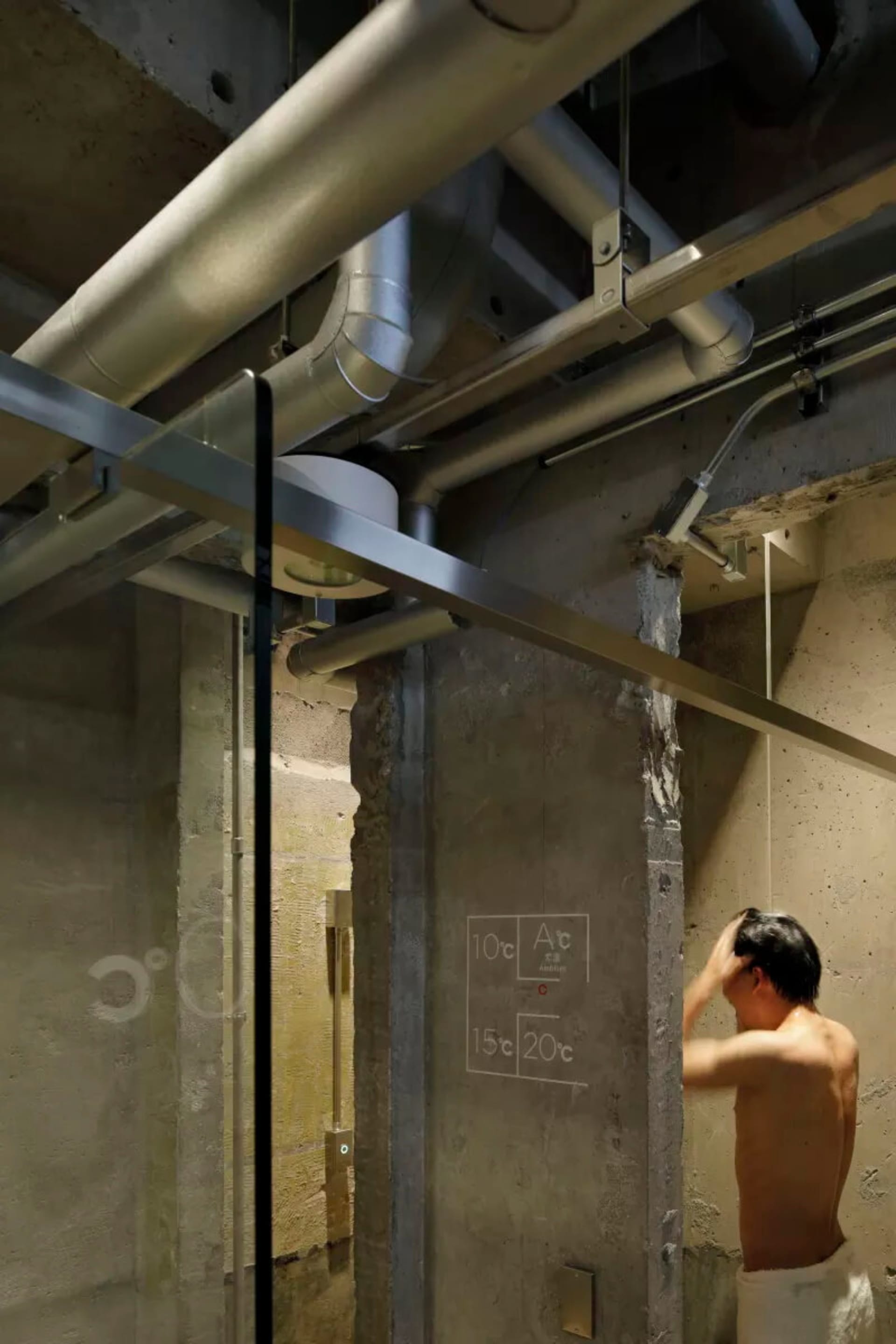 A minimalist industrial bathroom with concrete walls and exposed pipes