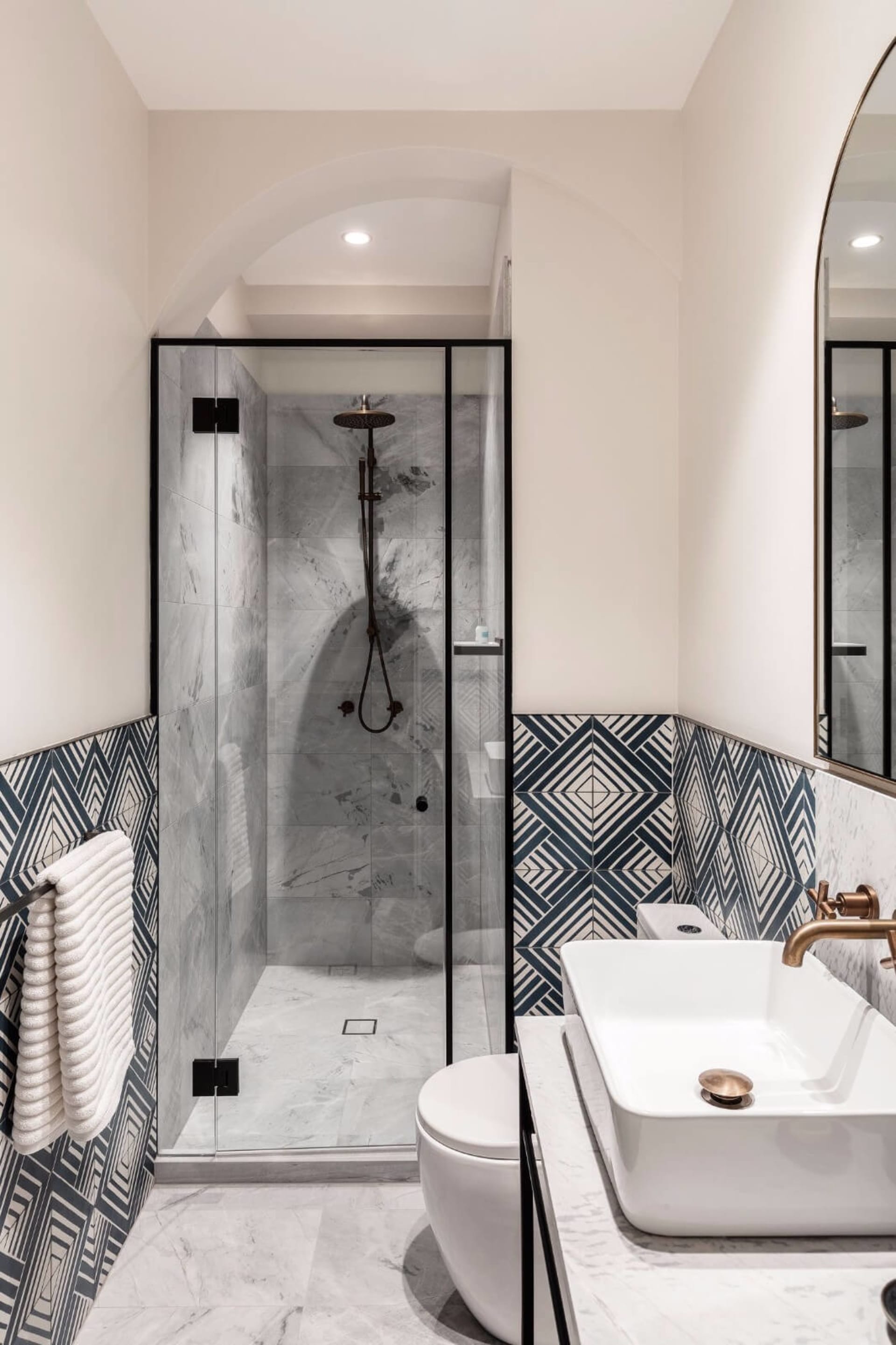 Modern minimalist bathroom featuring marble finishes and geometric tile patterns.