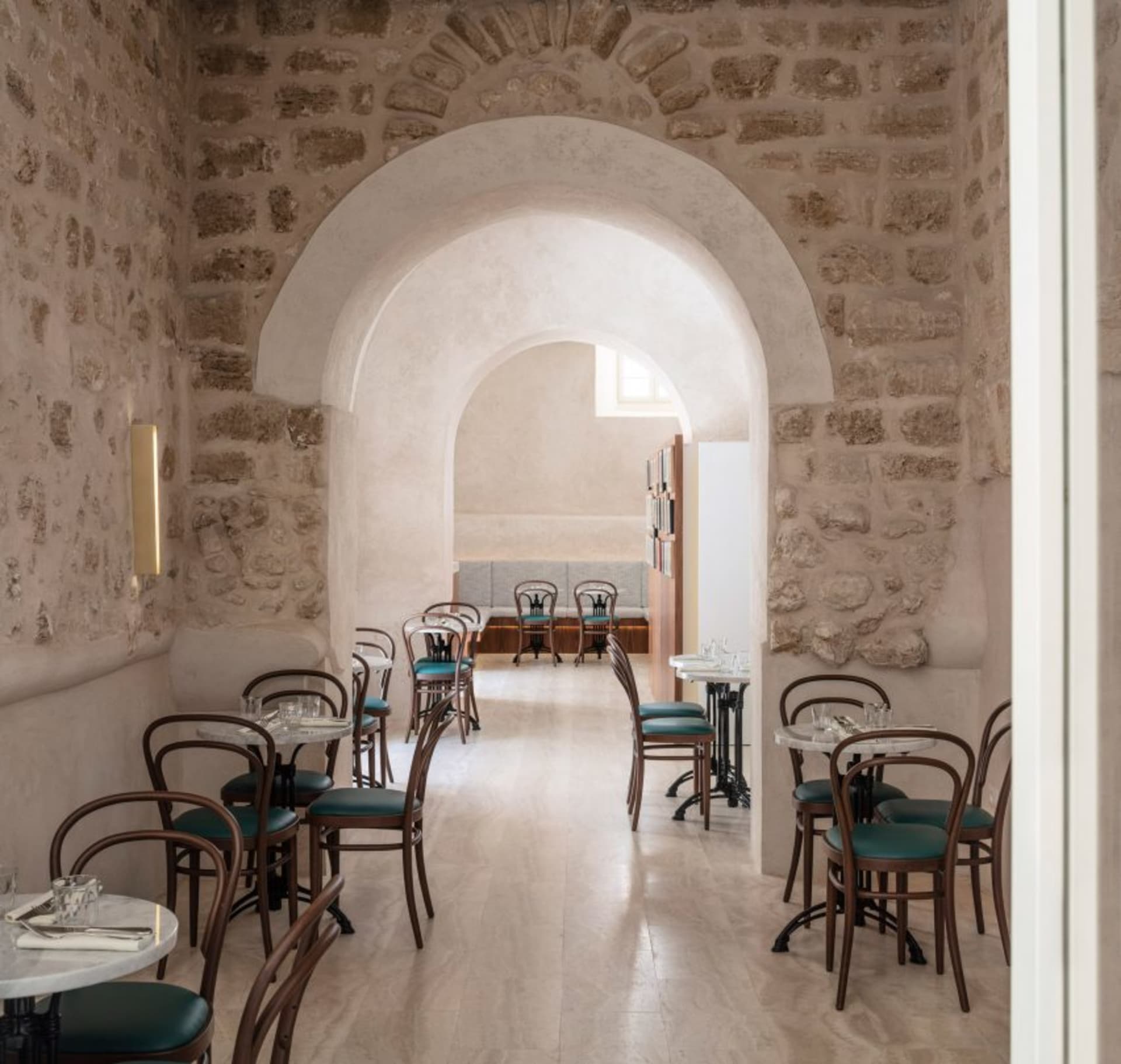 Modern minimalist cafe interior featuring stone walls and concrete flooring.