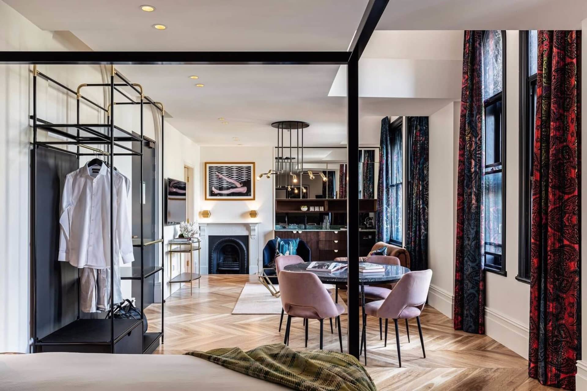 A modern dining room with a fireplace, wooden table, and patterned curtains.