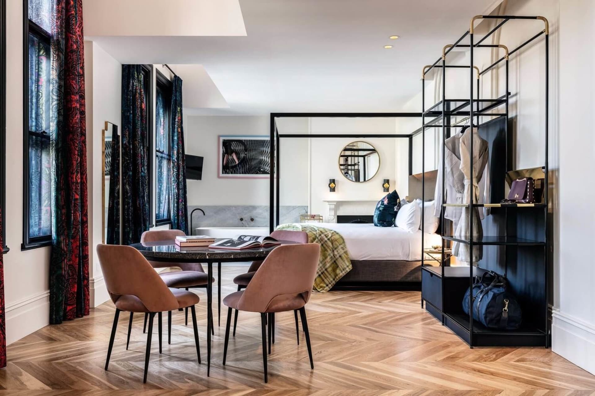 A modern hotel room suite featuring a wood floor, marble bathtub, and cloth.