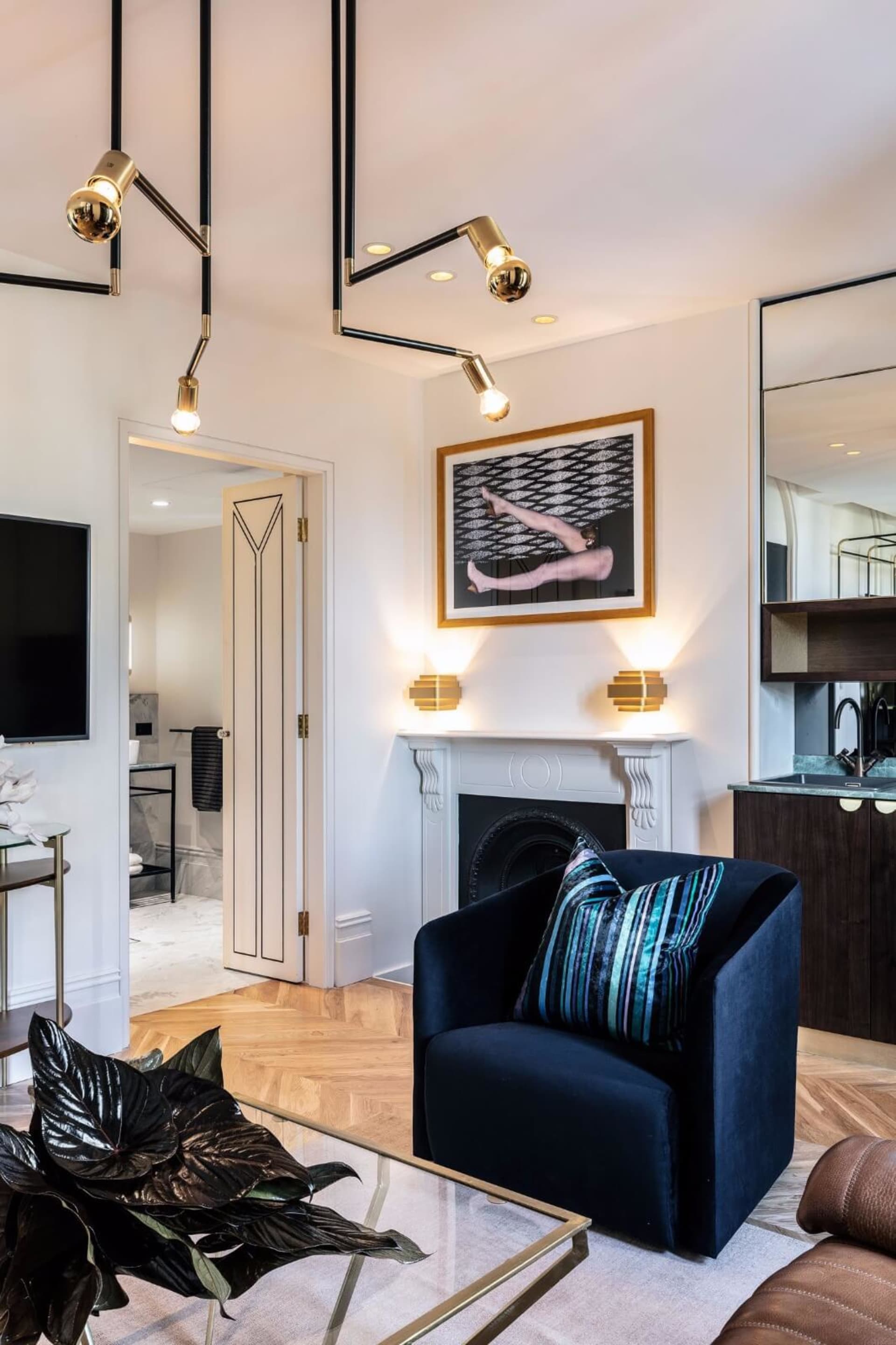 Modern living room with a velvet armchair, marble fireplace, and glass table.