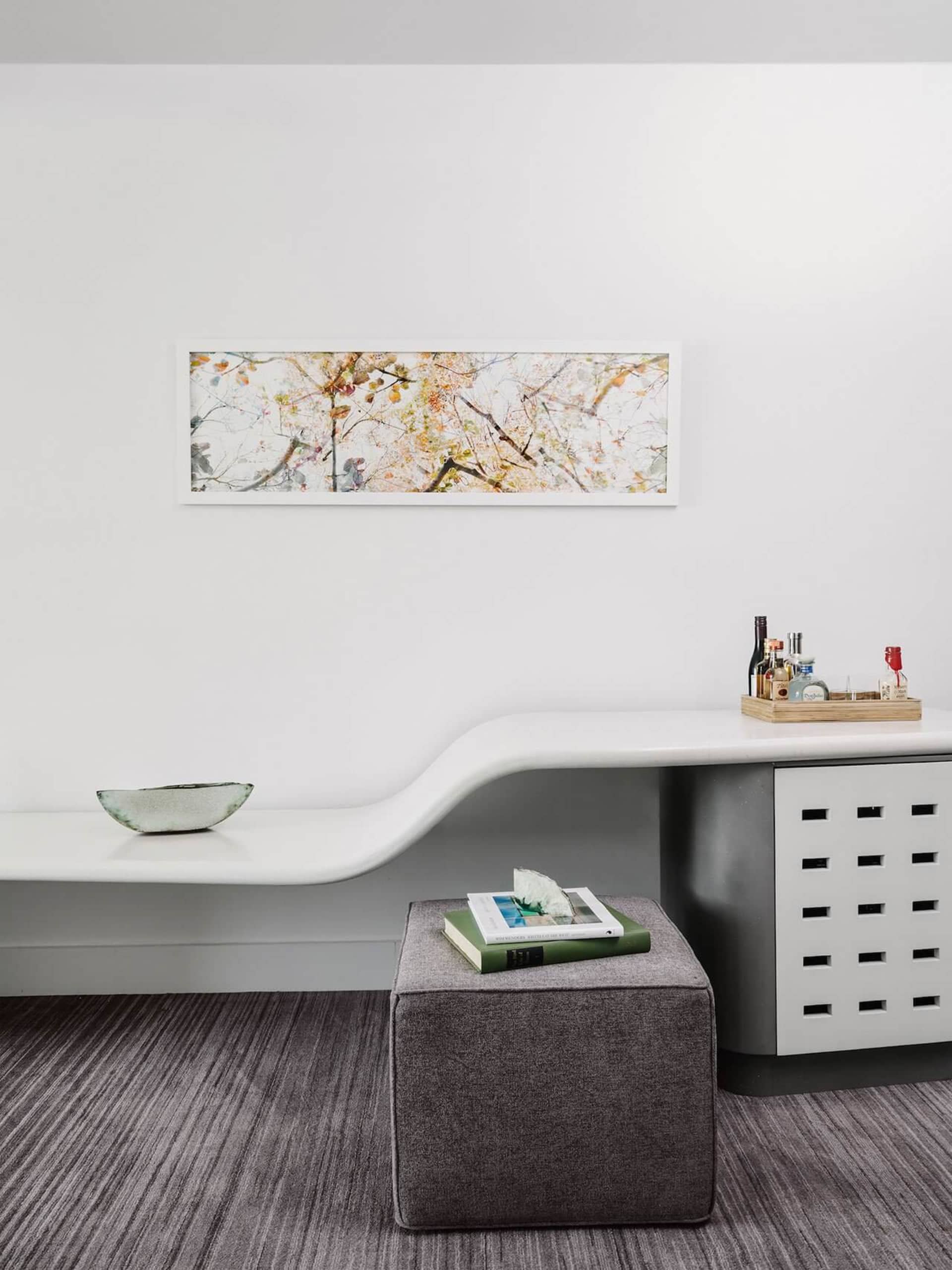 A modern minimalist living room with concrete furniture and a white geometric console table with a bowl on top.