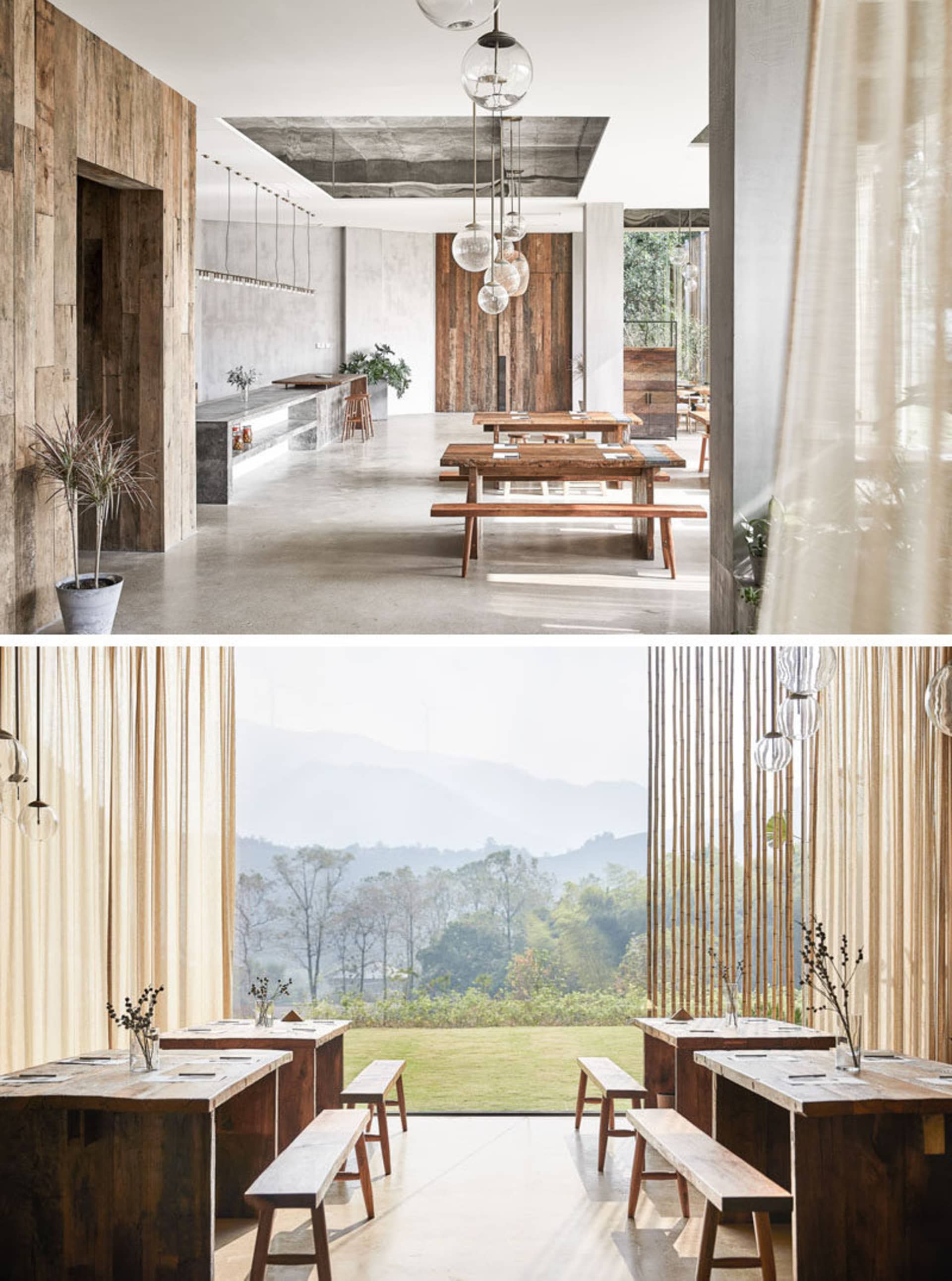 A modern restaurant interior with wooden benches, concrete floors, and a large window overlooking mountains.