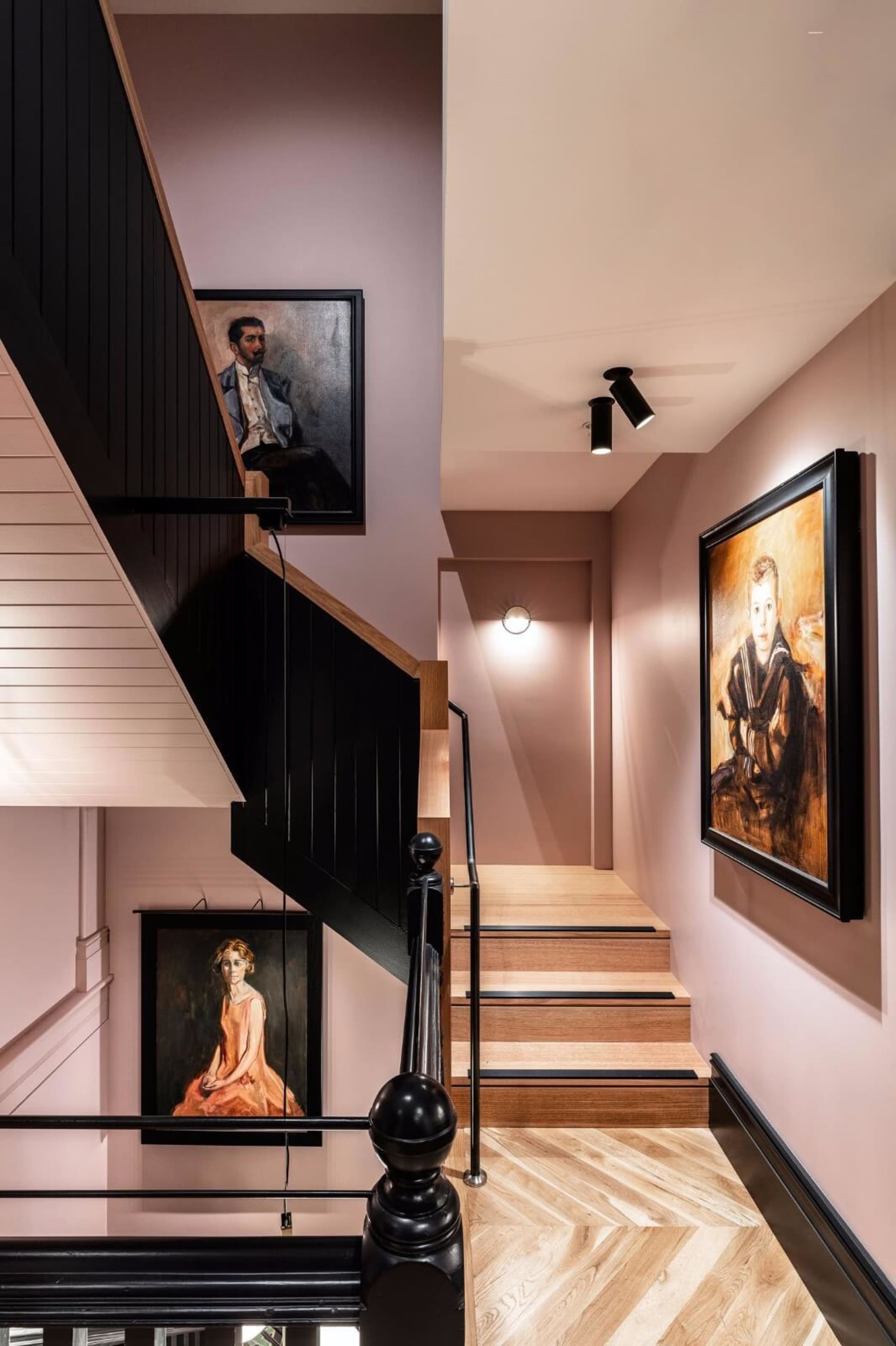 Modern staircase featuring black railings, wooden steps, and framed artworks on the walls.