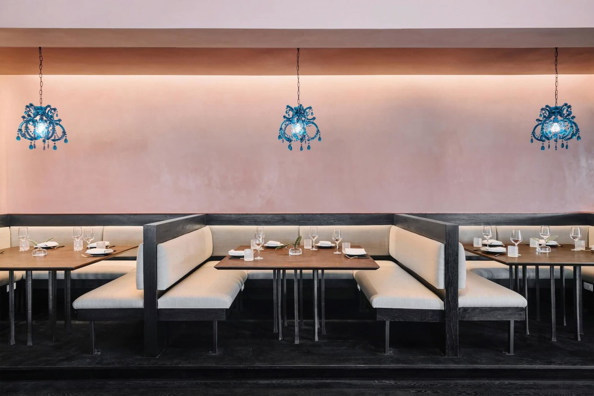 A restaurant interior with booth seating and blue chandelier lighting.