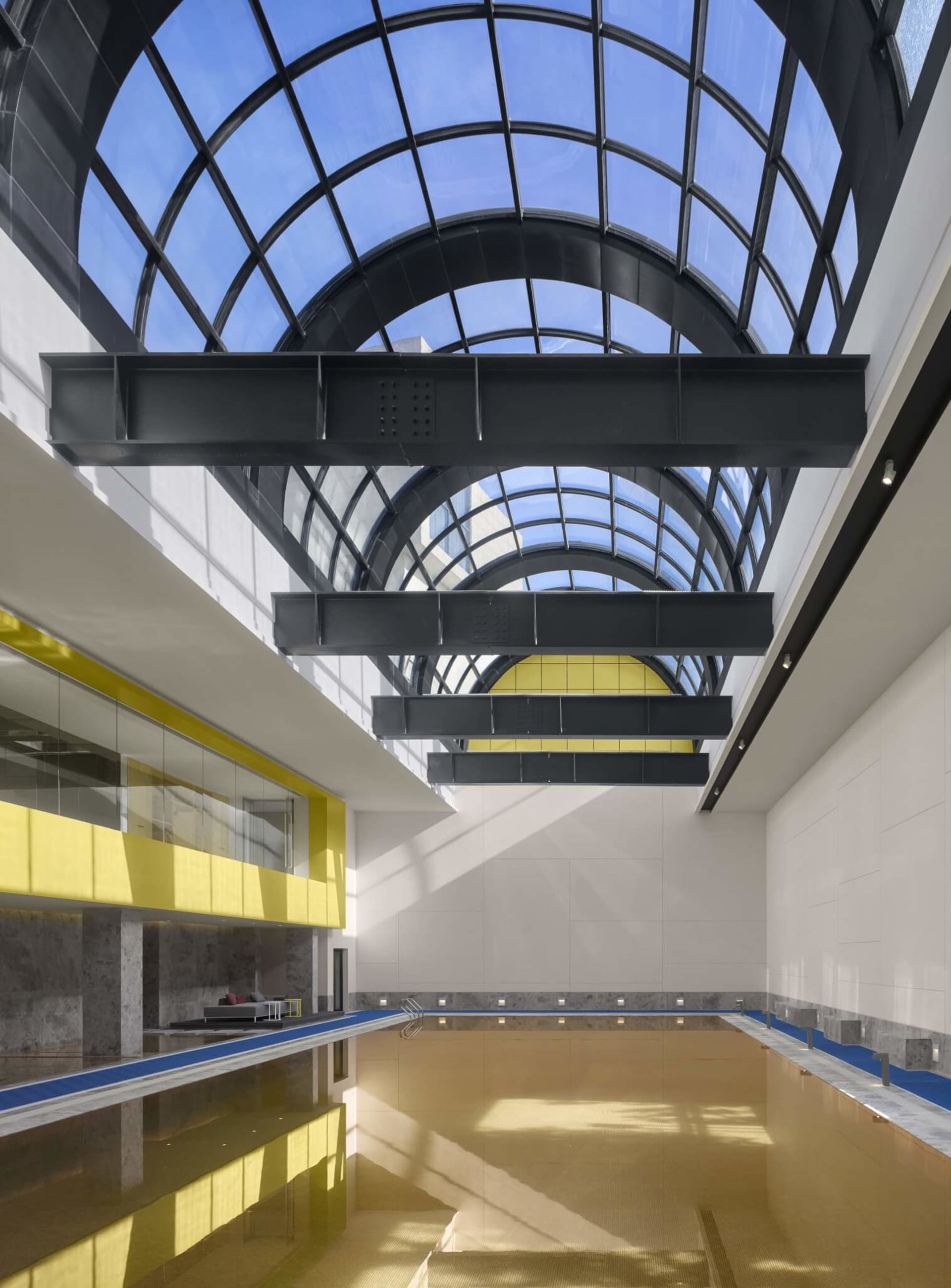 Modern glass indoor pool with a glass ceiling and minimalist design.