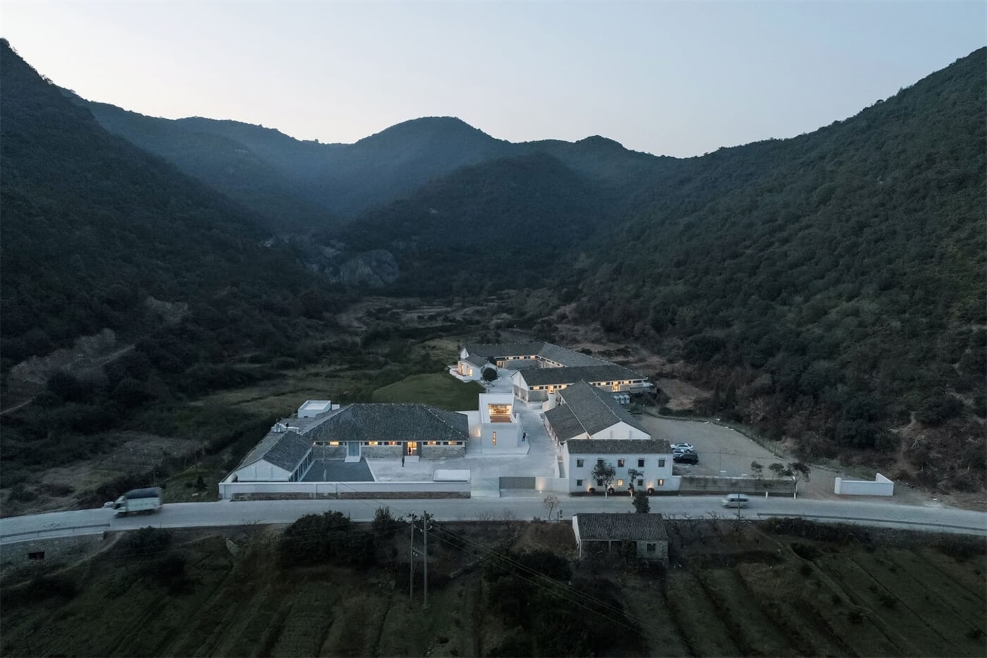 俯瞰現代住宅大樓,白色混凝土外觀,四周環繞綠意山景。