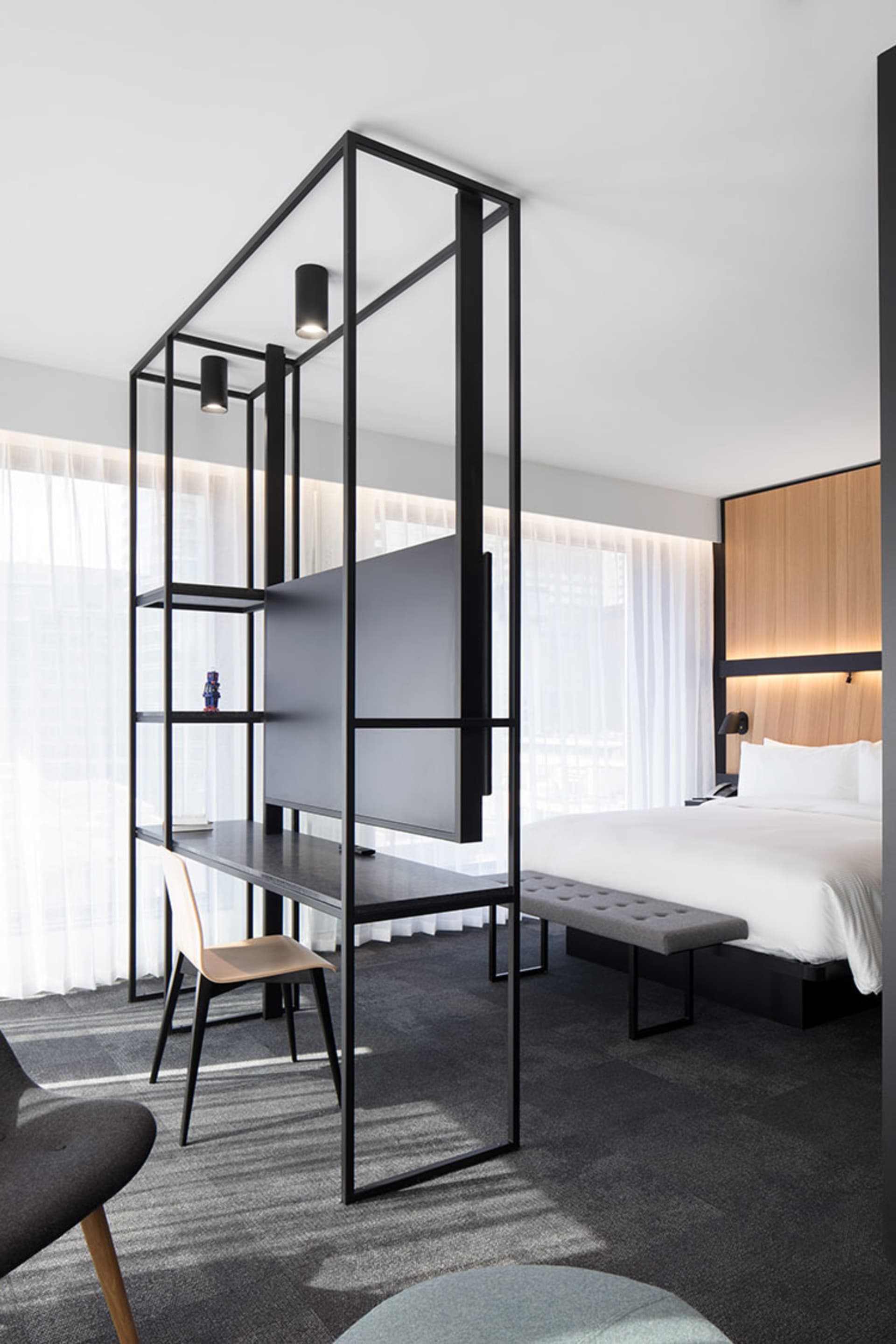 Modern bedroom featuring a minimalist design with black metal frame, glass, and fabric elements.