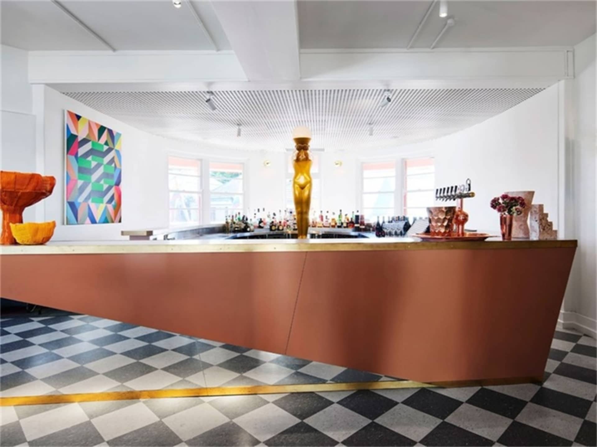 現代酒吧室內,展示金屬與木質吧台,牆面掛有幾何藝術作品。