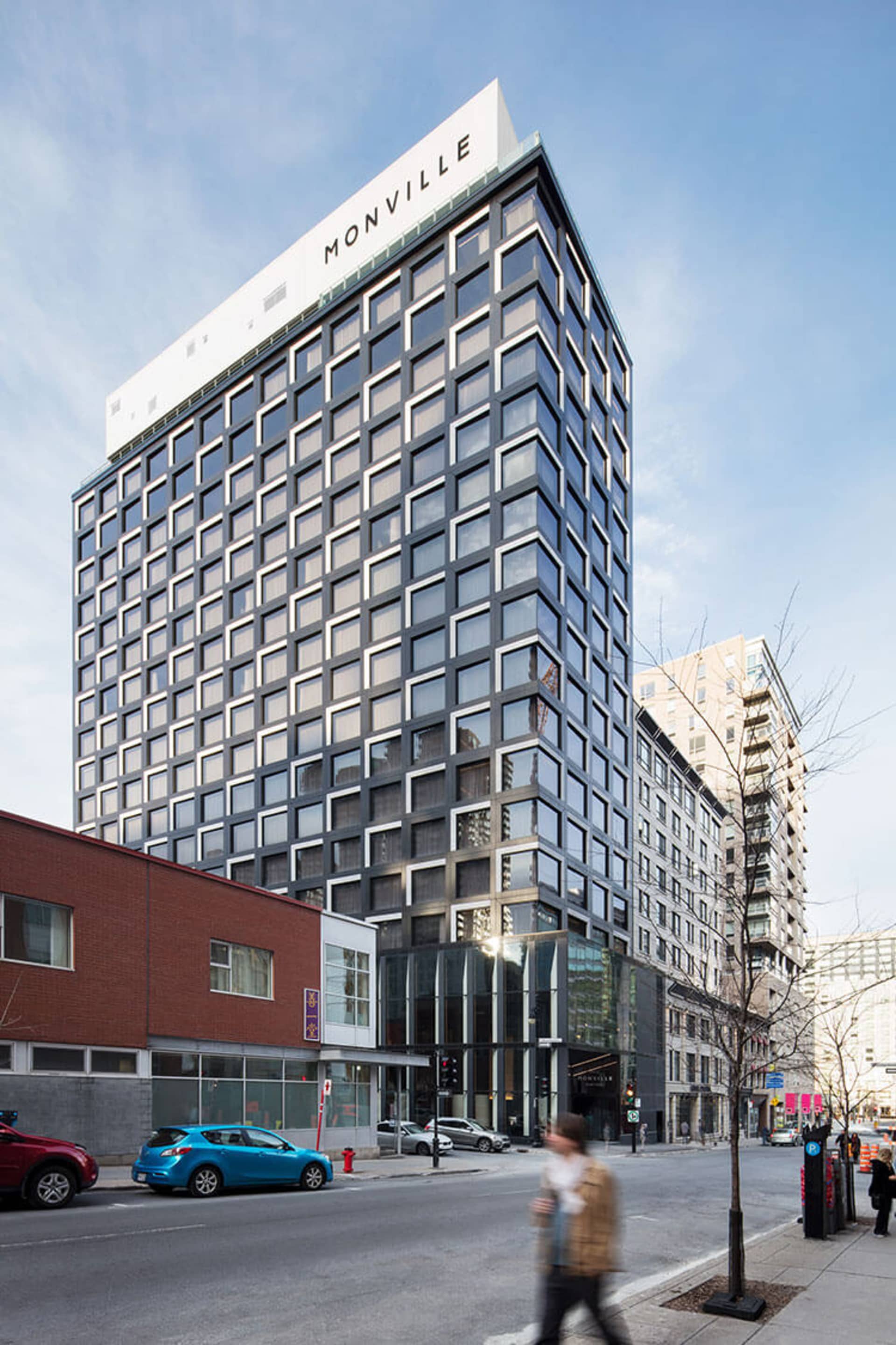 A tall, modern building with glass and concrete facade in an urban setting, featuring the word 'MONVILLE' on the top.