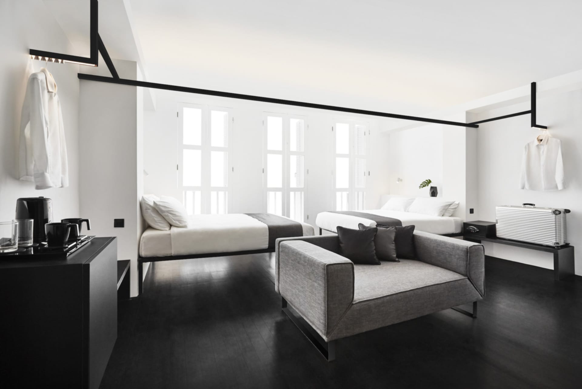 A modern bedroom interior with neutral-colored furnishings, featuring two beds and a minimalist design.