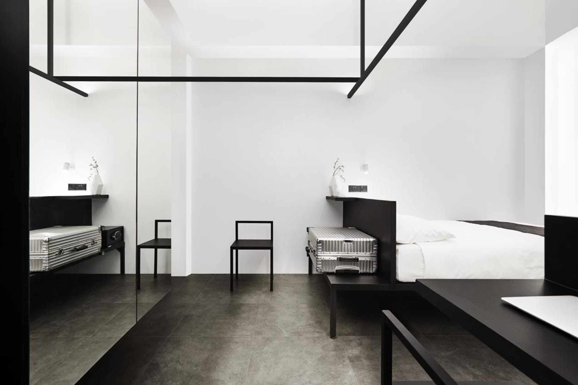 Modern minimalist bedroom featuring black and white decor with metallic luggage and furniture.