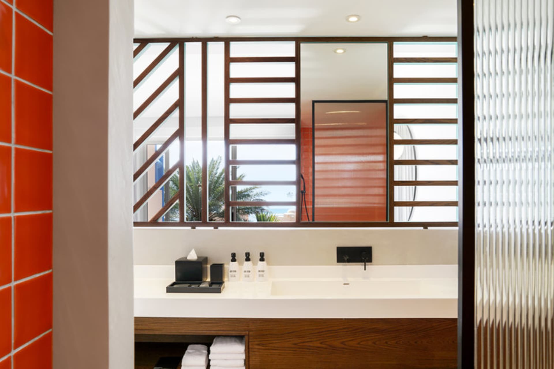 Modern minimalist bathroom featuring glass tiles and wood elements.