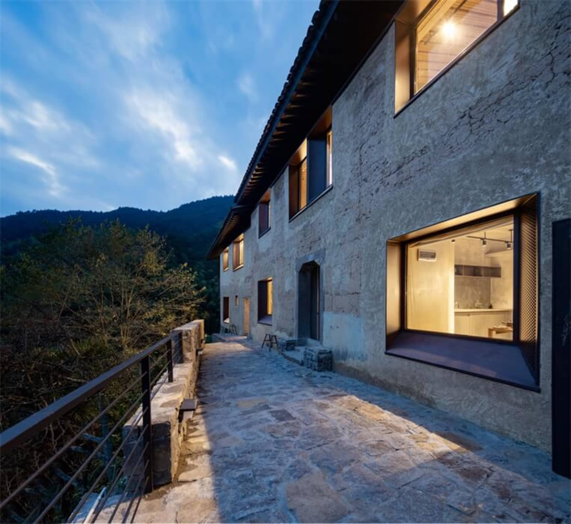現代住宅外觀,混凝土牆面、大型窗戶,以及通往入口的石板步道。
