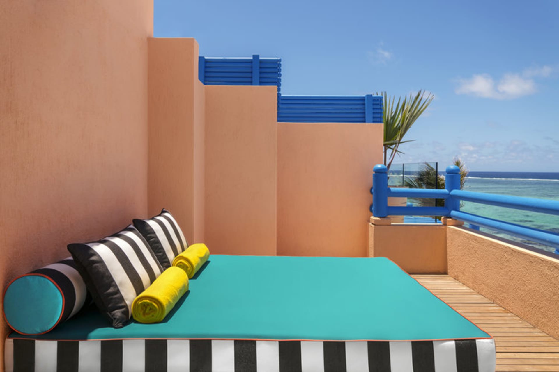 A modern residential design featuring a deck with blue and black striped textiles and yellow towels, set against a peach-colo