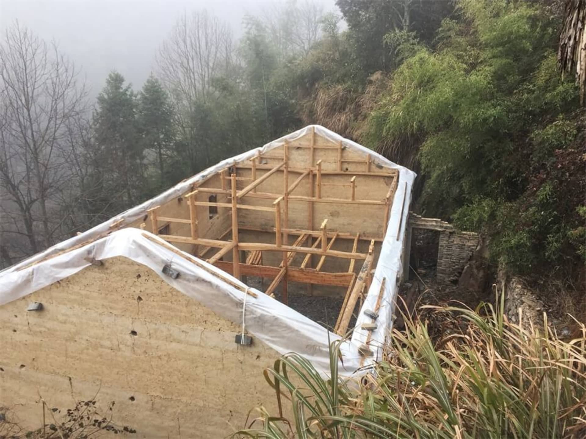 一座木框架結構的建築工地，覆蓋著白色塑膠布