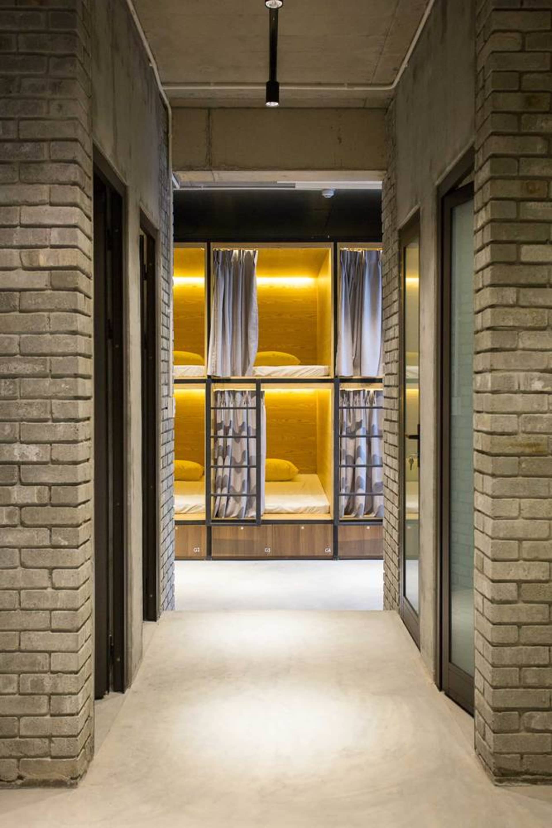 Industrial-style accommodation room with concrete walls and bed pods in a hostel.