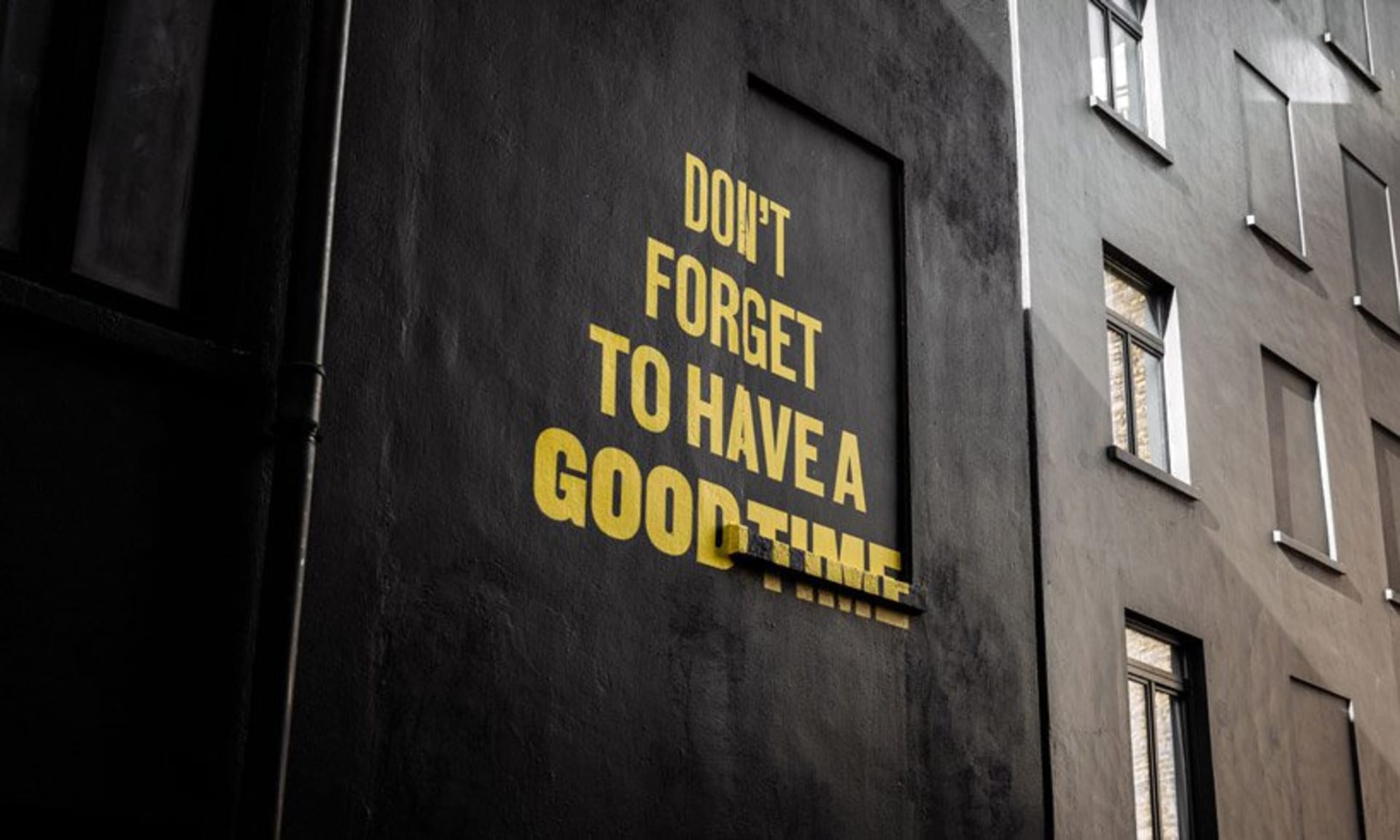 A black wall with yellow text that says 'Don’t forget to have a good time'.