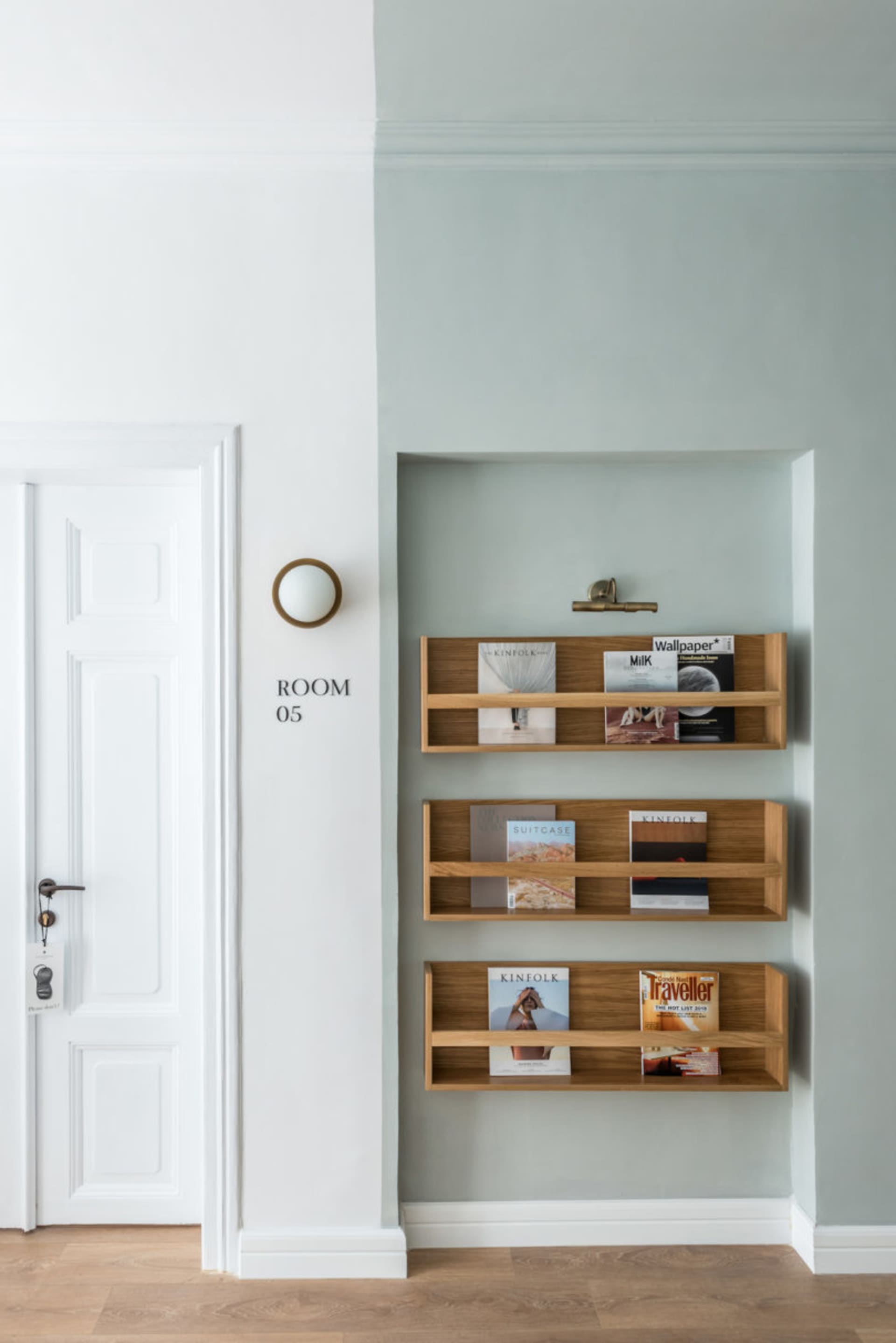 A minimalist home library featuring wooden shelves with magazines and books displayed.