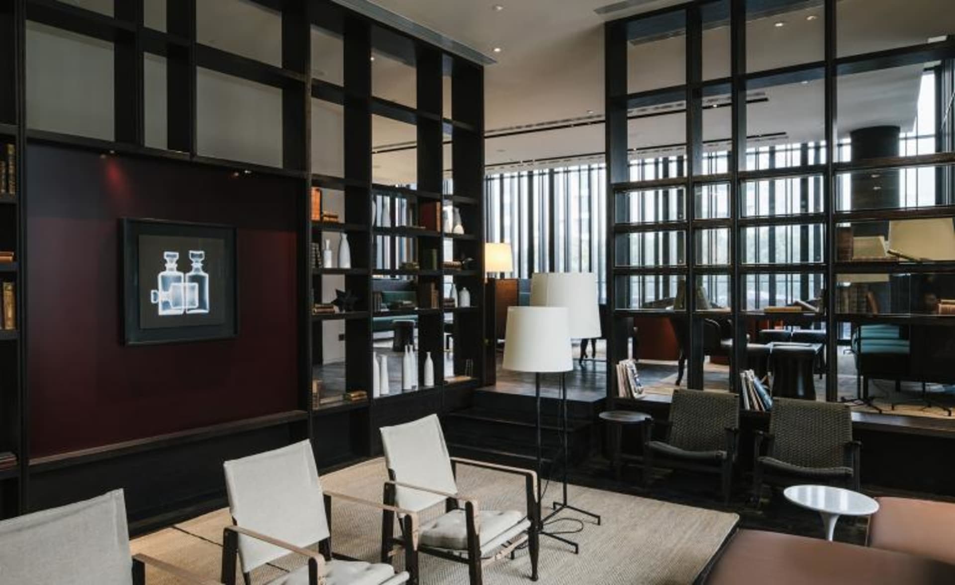 Modern hotel lobby with minimalist design featuring white chairs, floor lamps, and bookshelves.