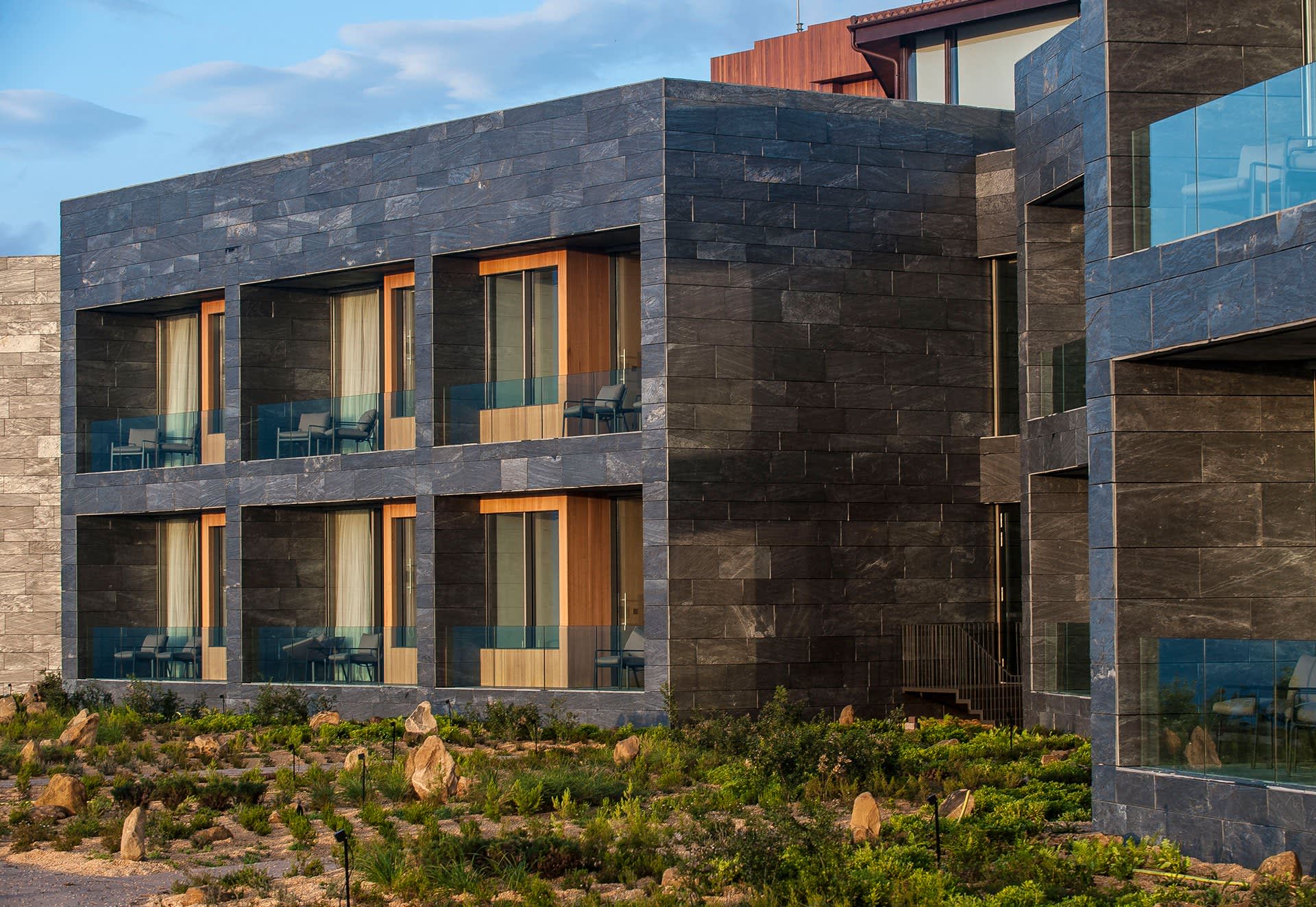 Modern hotel suite with stone exterior and glass windows and balconies.
