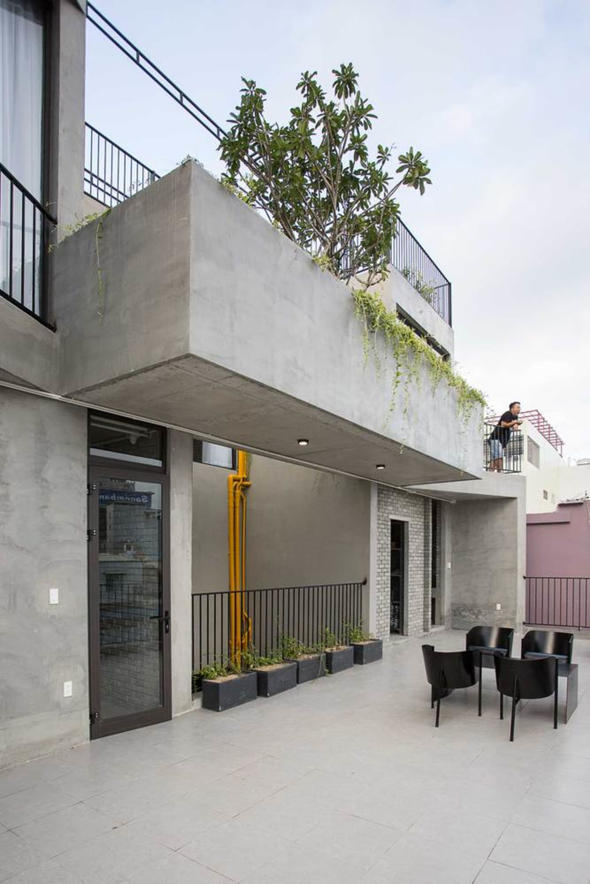 Modern residential terrace featuring a glass wall and a concrete patio with potted plants.