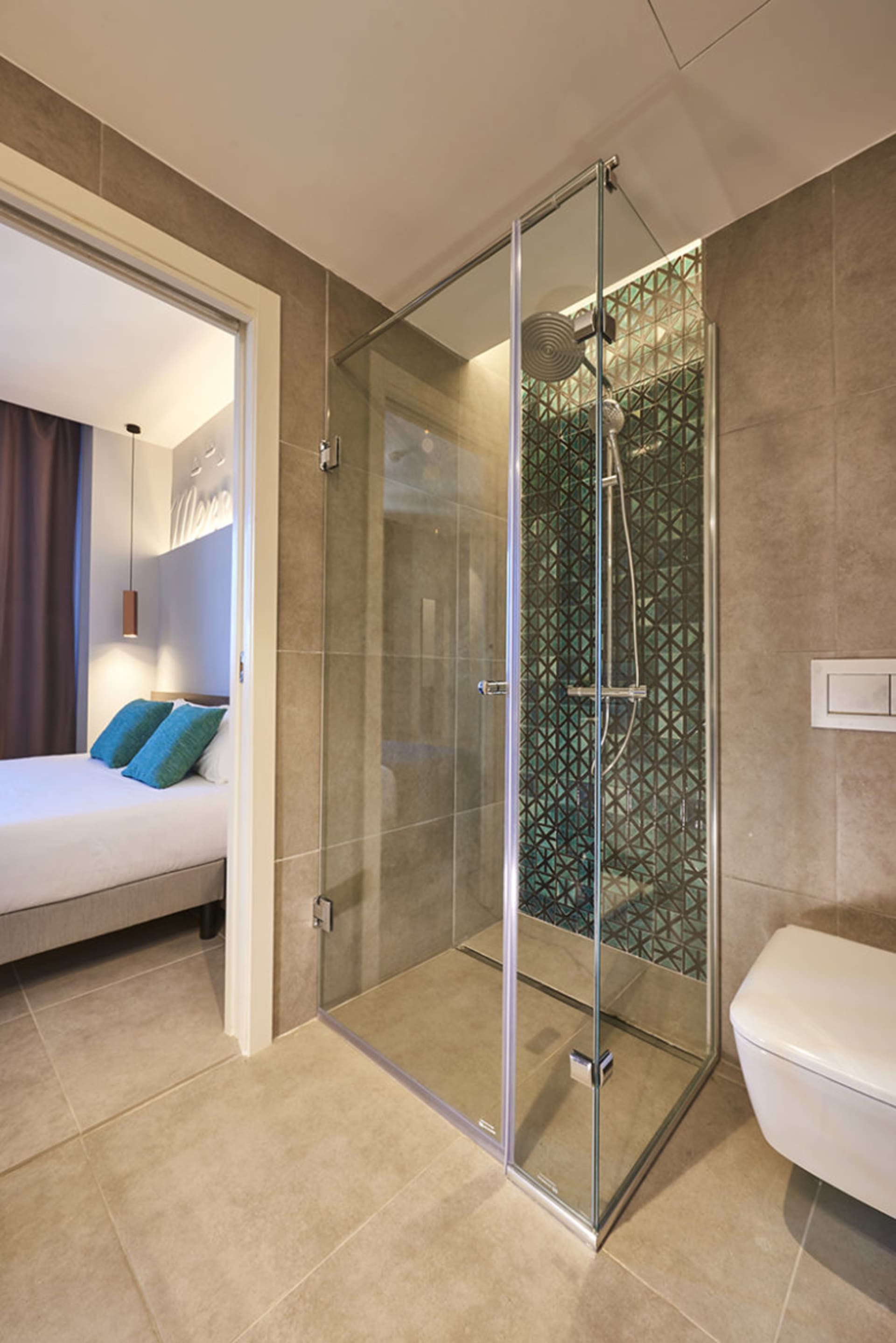 Modern bathroom interior featuring a glass shower enclosure with a geometric pattern on the tile wall.