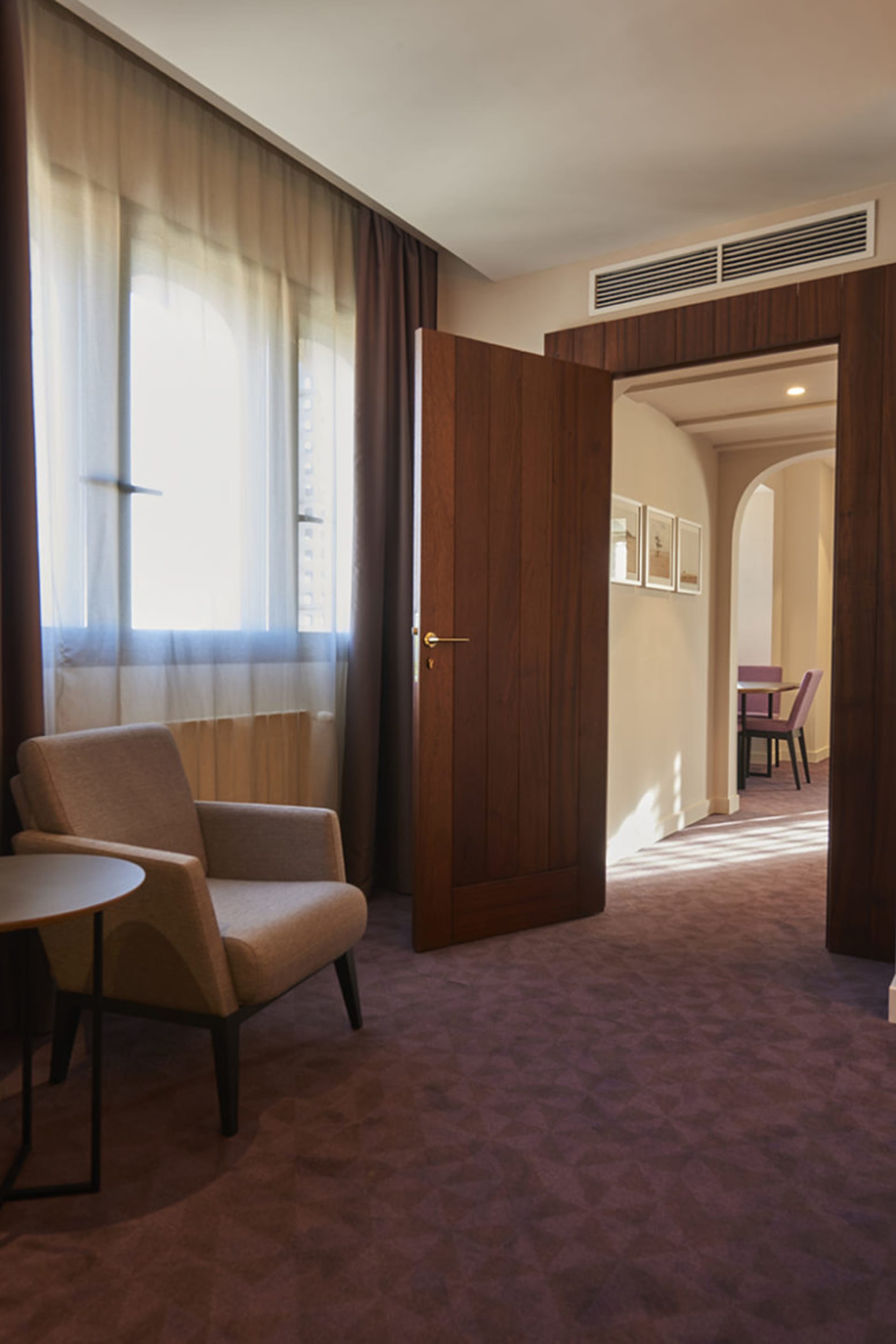 A modern hotel suite featuring wooden furnishings and a large window.