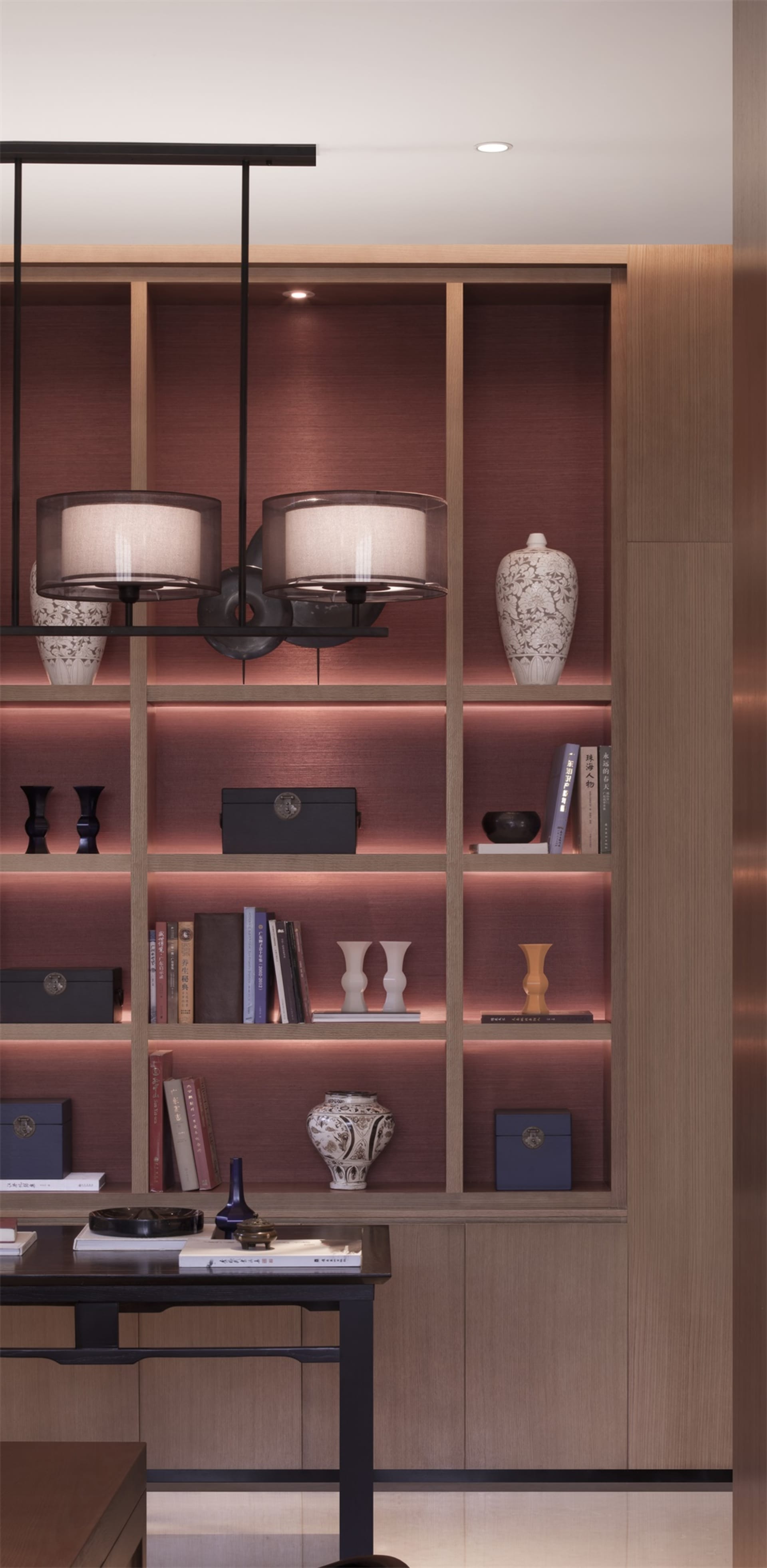 A modern library shelf with wooden construction, displaying books, vases, and decorative items with ambient lighting.