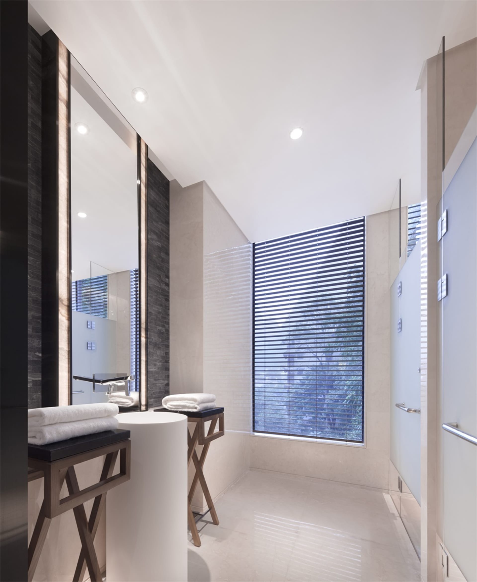 A modern bathroom featuring marble tiles and a large window with blinds.