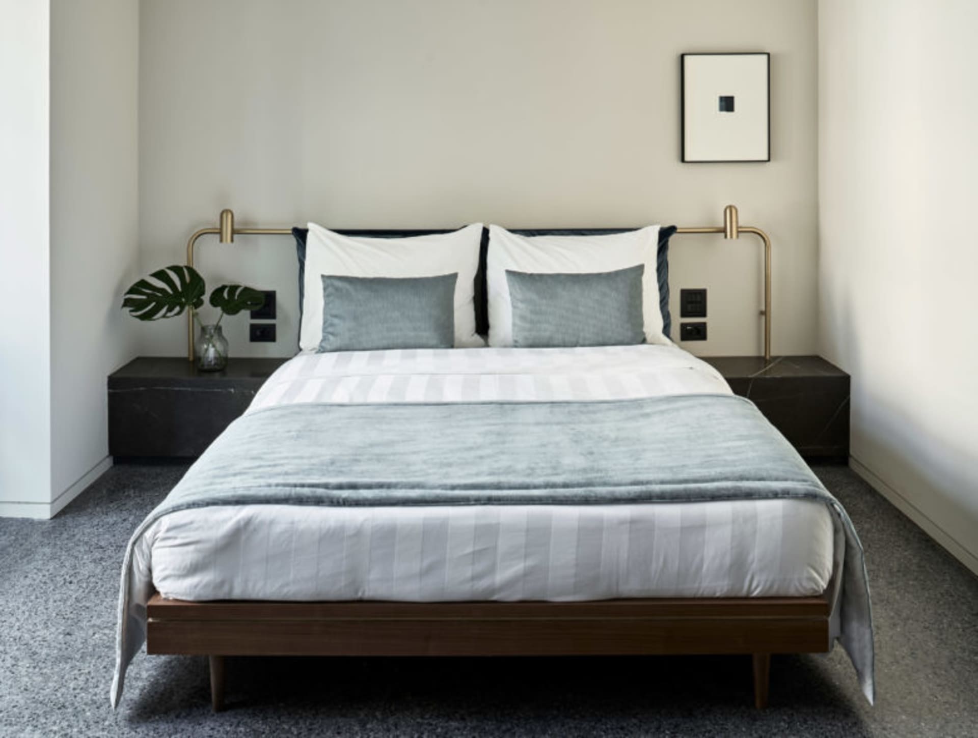 Modern minimalist bedroom featuring a wooden bed frame with metal handles, white bedding, and dark grey accents.