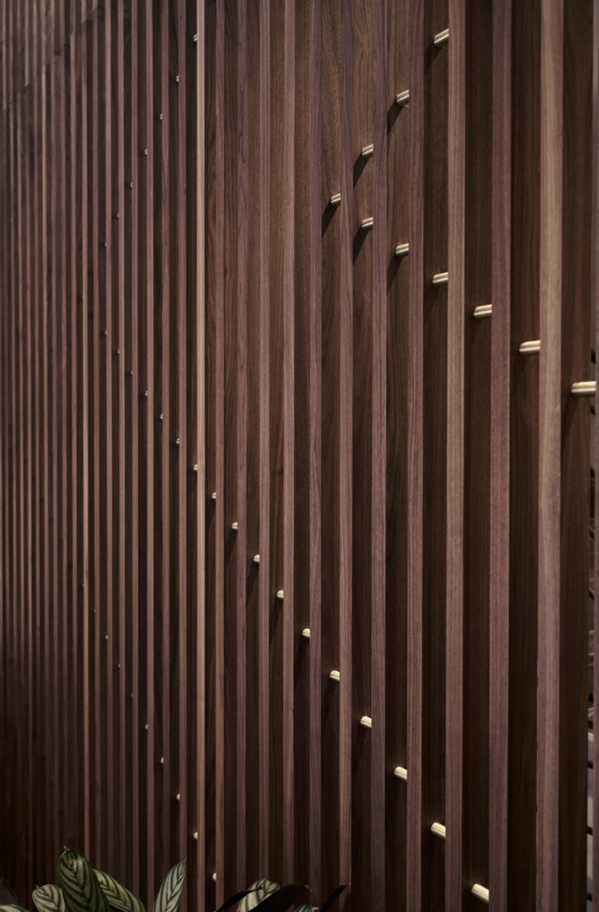 A close-up view of a wood-paneled wall with vertical slats and metallic accents.
