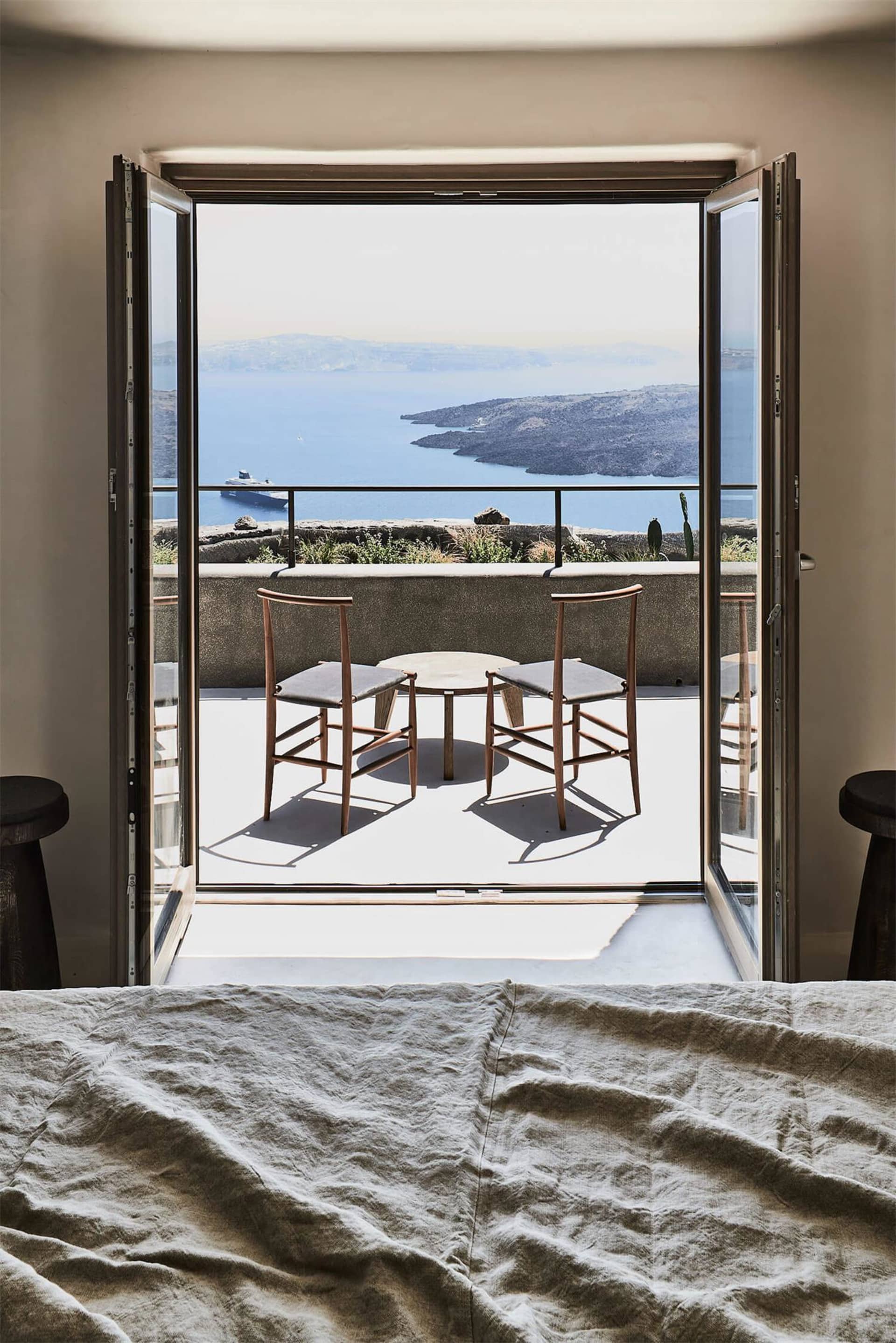 A minimalist bedroom featuring wooden furniture and a view of the sea.