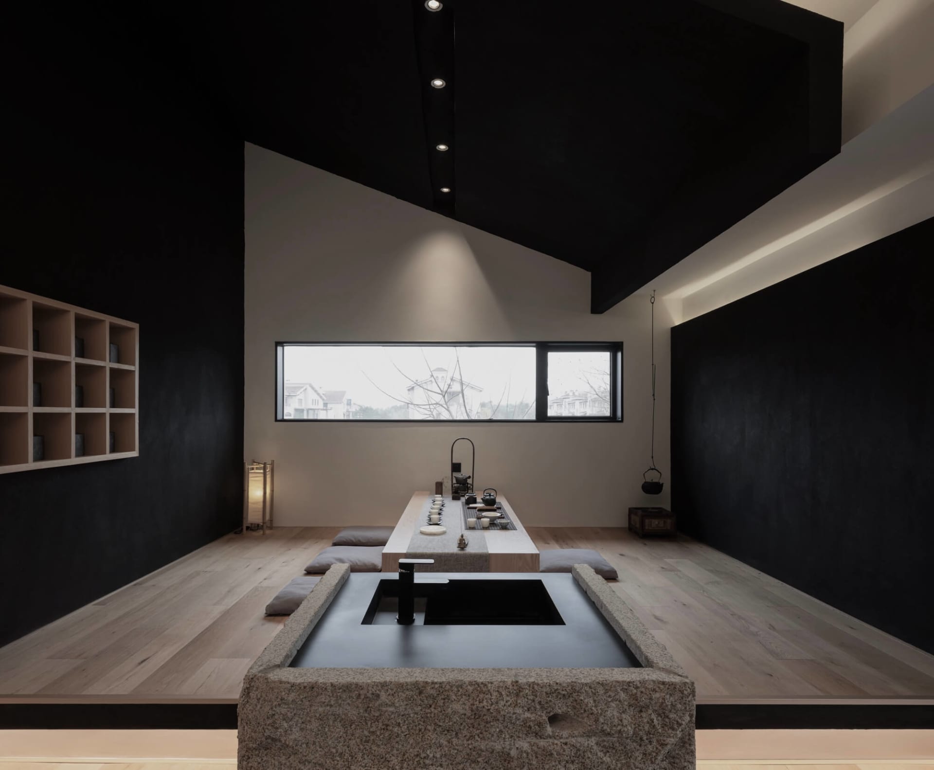 A minimalist tea room featuring teak furniture and a stone water basin.