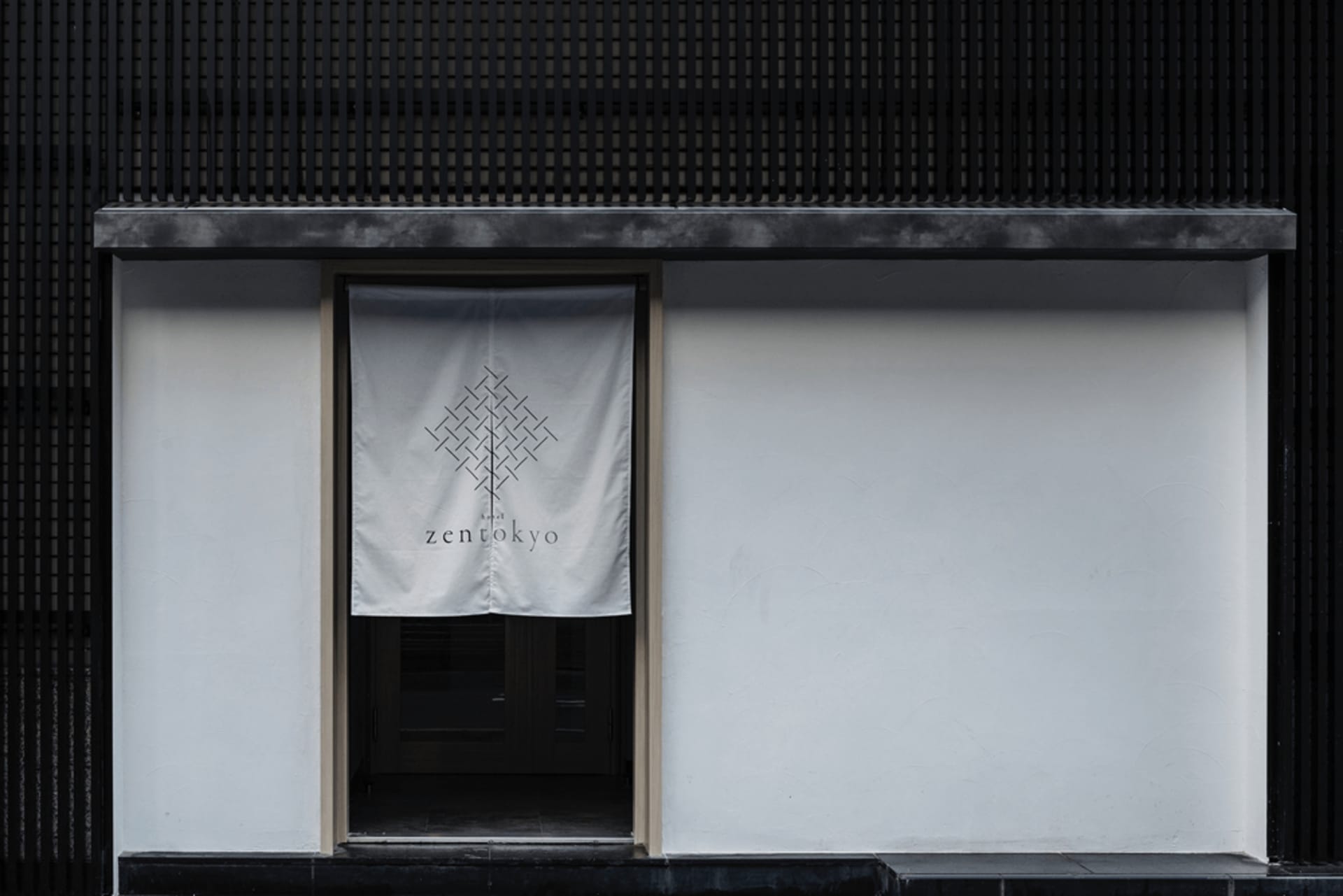 A storefront with a white banner featuring a geometric pattern and the text 'Zen Tokyo'. The storefront has a white wall and 