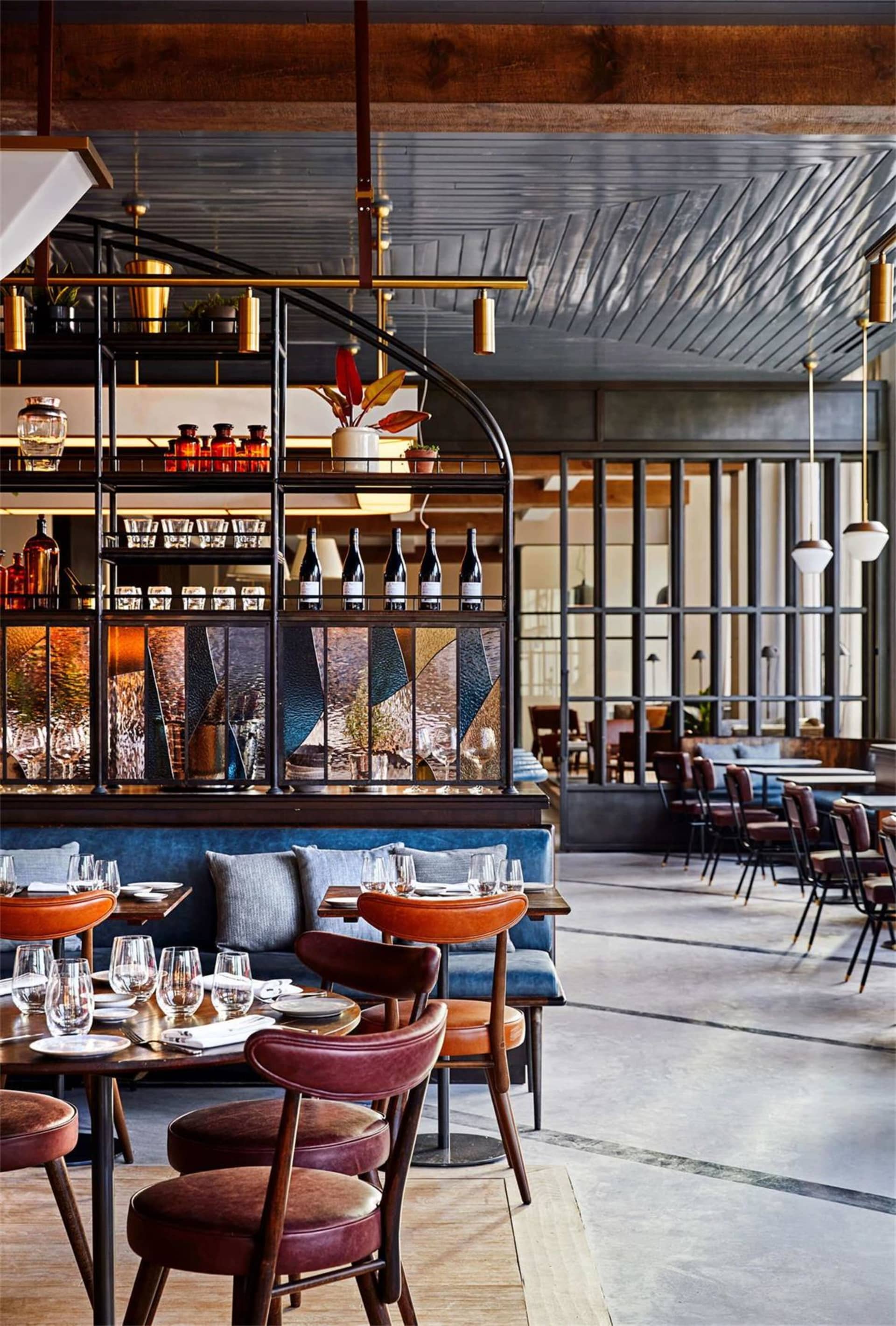 Industrial-style restaurant interior with metal shelving, wooden tables, and glass decor elements.