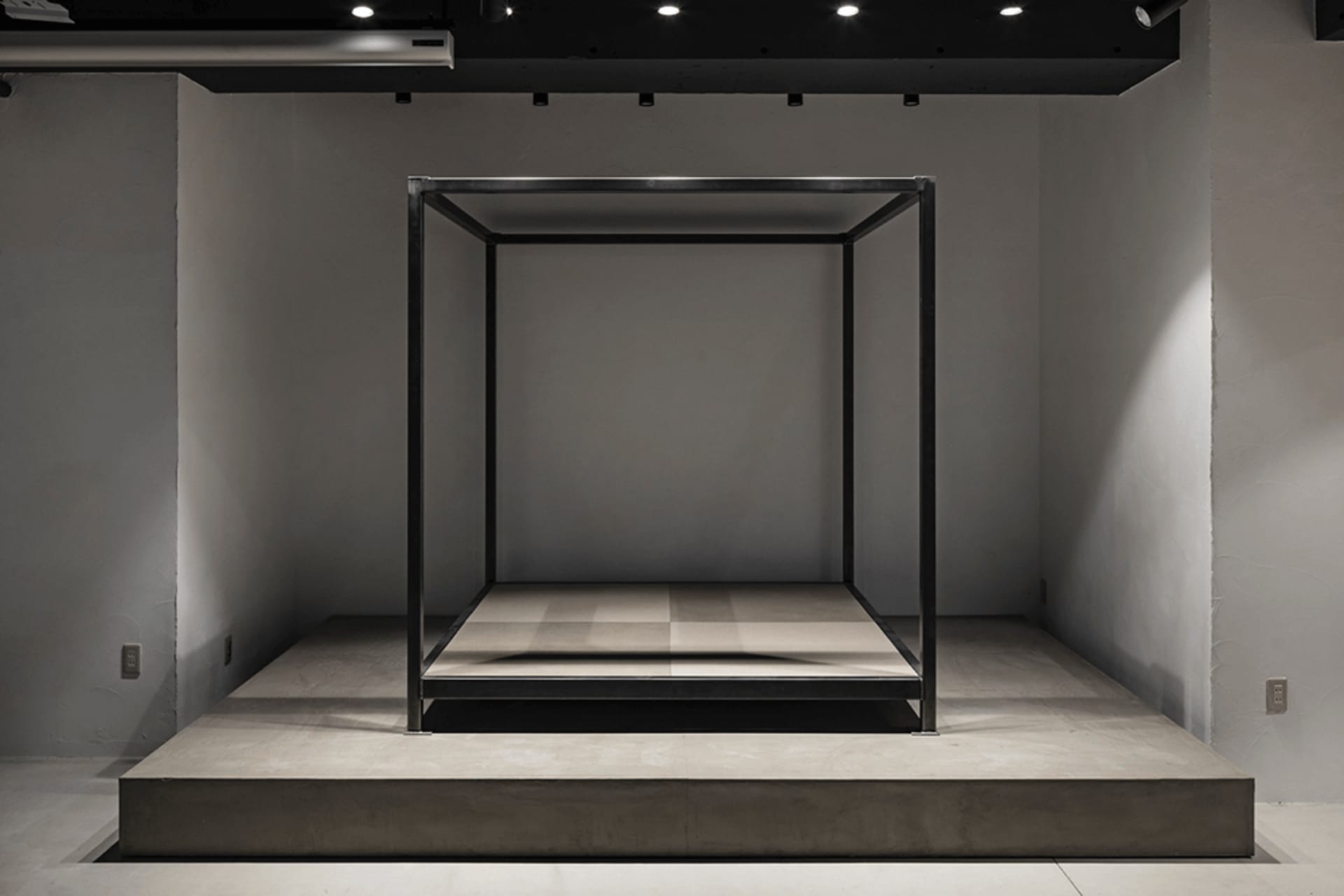 A minimalist metal frame structure on a concrete platform