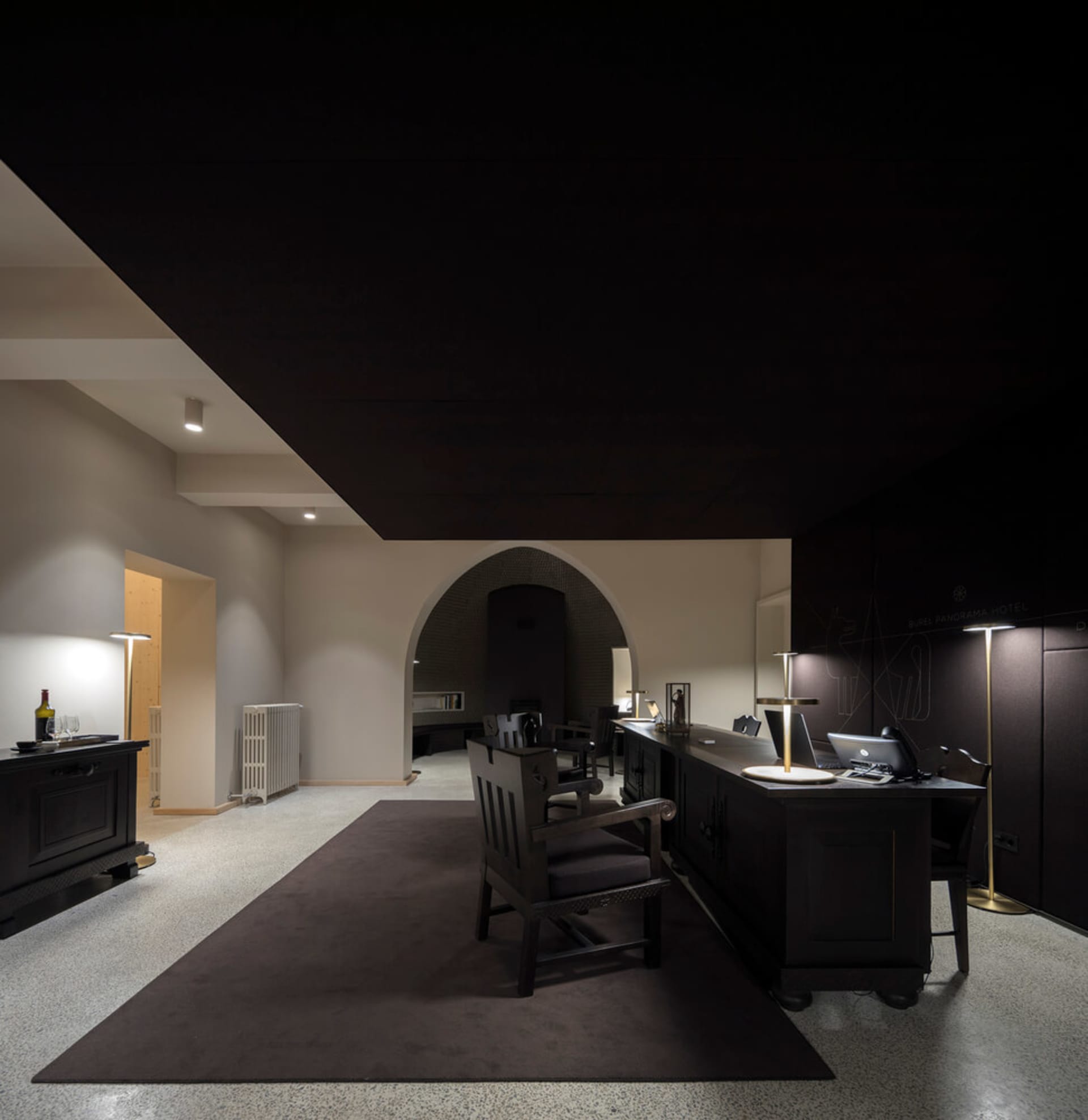 An office space with a minimalist design, featuring black furniture on a carpeted floor.